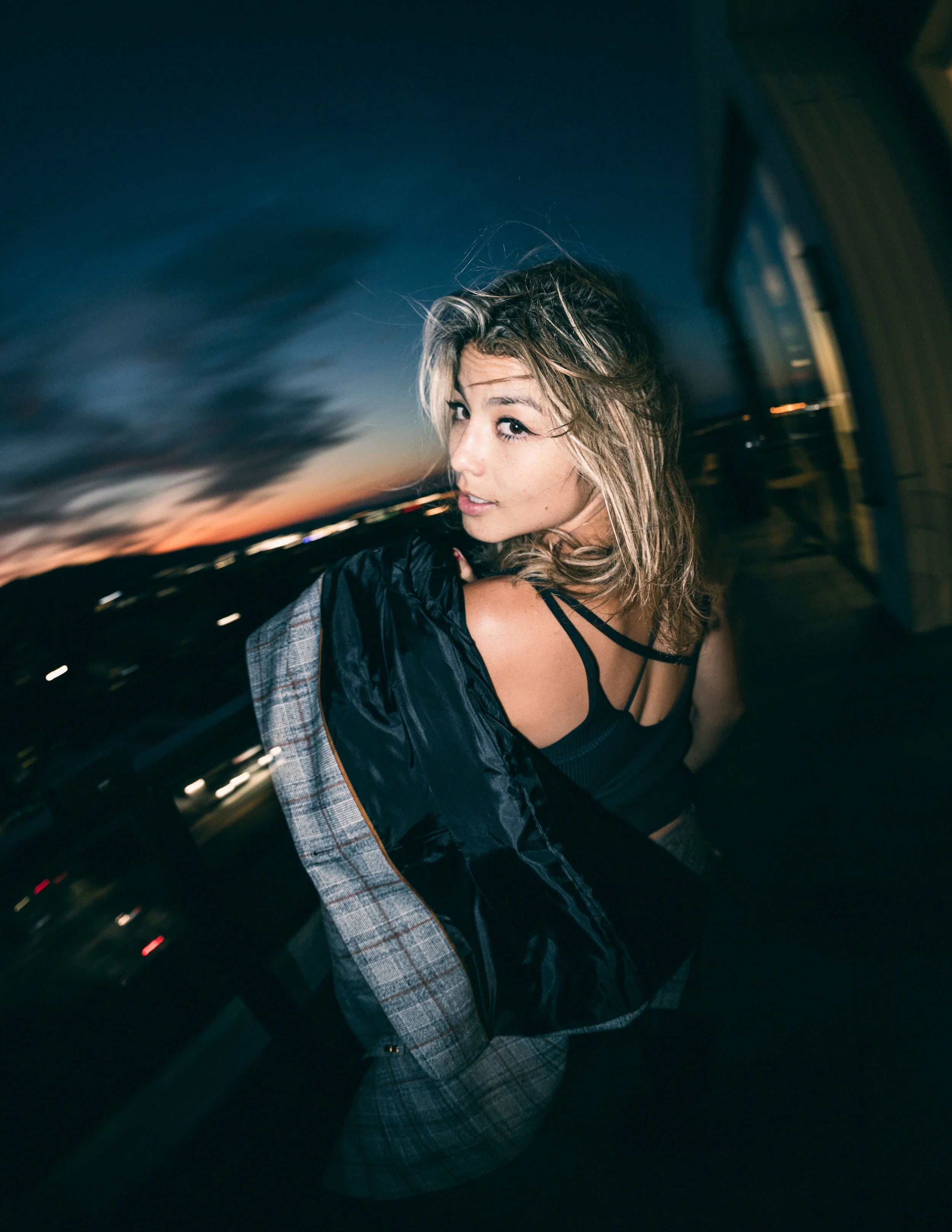 Model, Kim Gonzalez, on a PDX rooftop at sunset holding a Calvin Klein jacket over her shoulder. Portland fashion photography by JP Bogan.