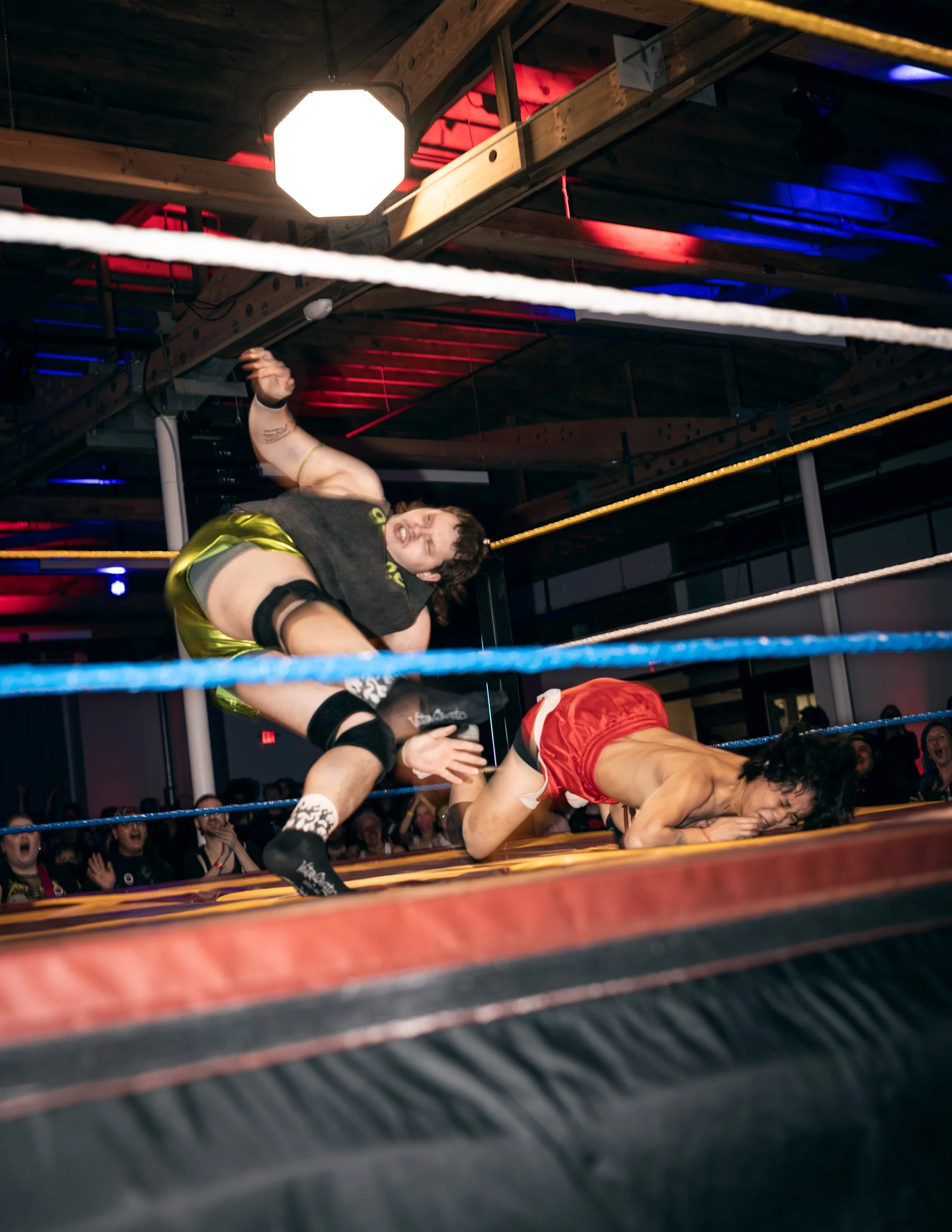 Two trans wrestlers flying across the ring at TBOY Wrestling in Portland, OR.