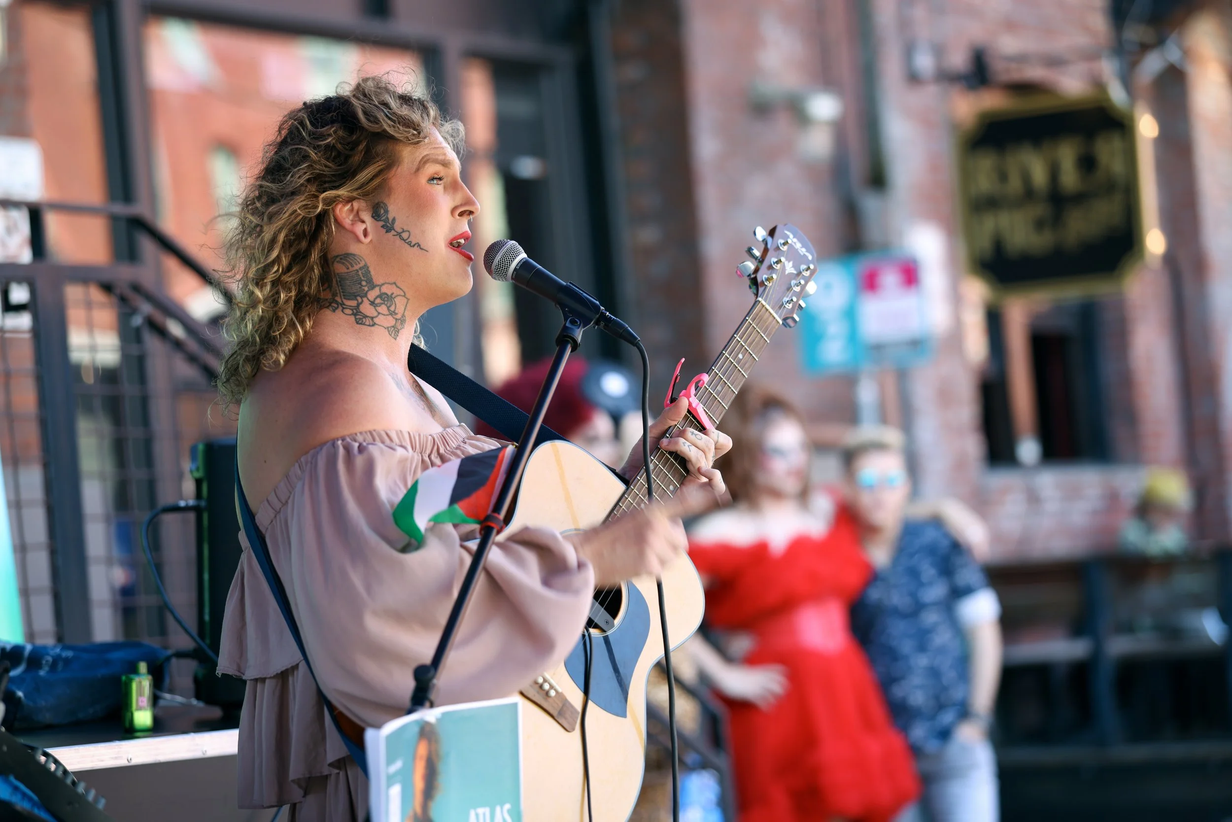 A woman playing guitar and singing at the Pearl Summer Party in downtown Portland, OR.
