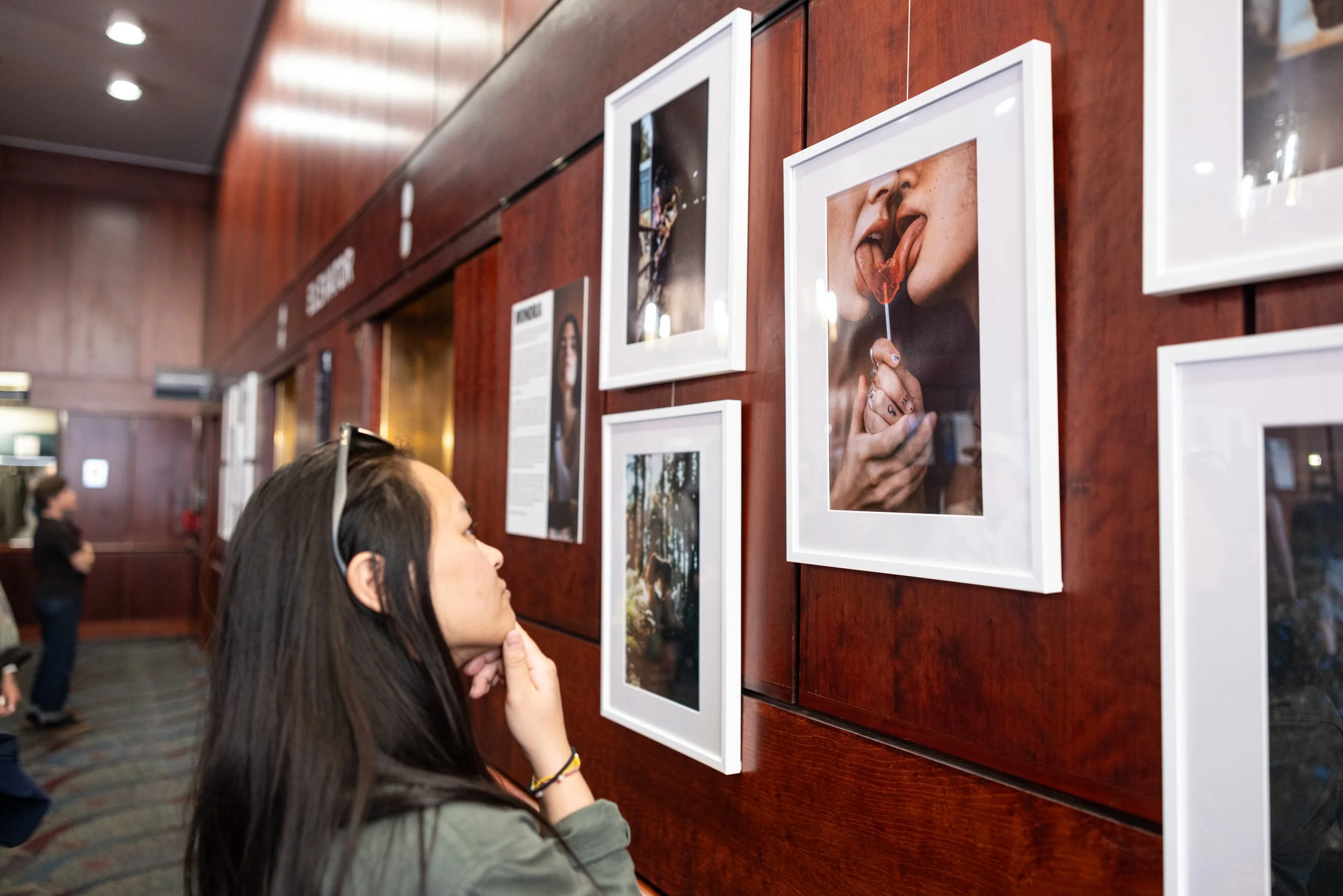 Summer Luu looking at exhibition at Framing Our Presence event at Portland 5 Winningstad Theater in Portland, Oregon. Event Photography bu JP Bogan.