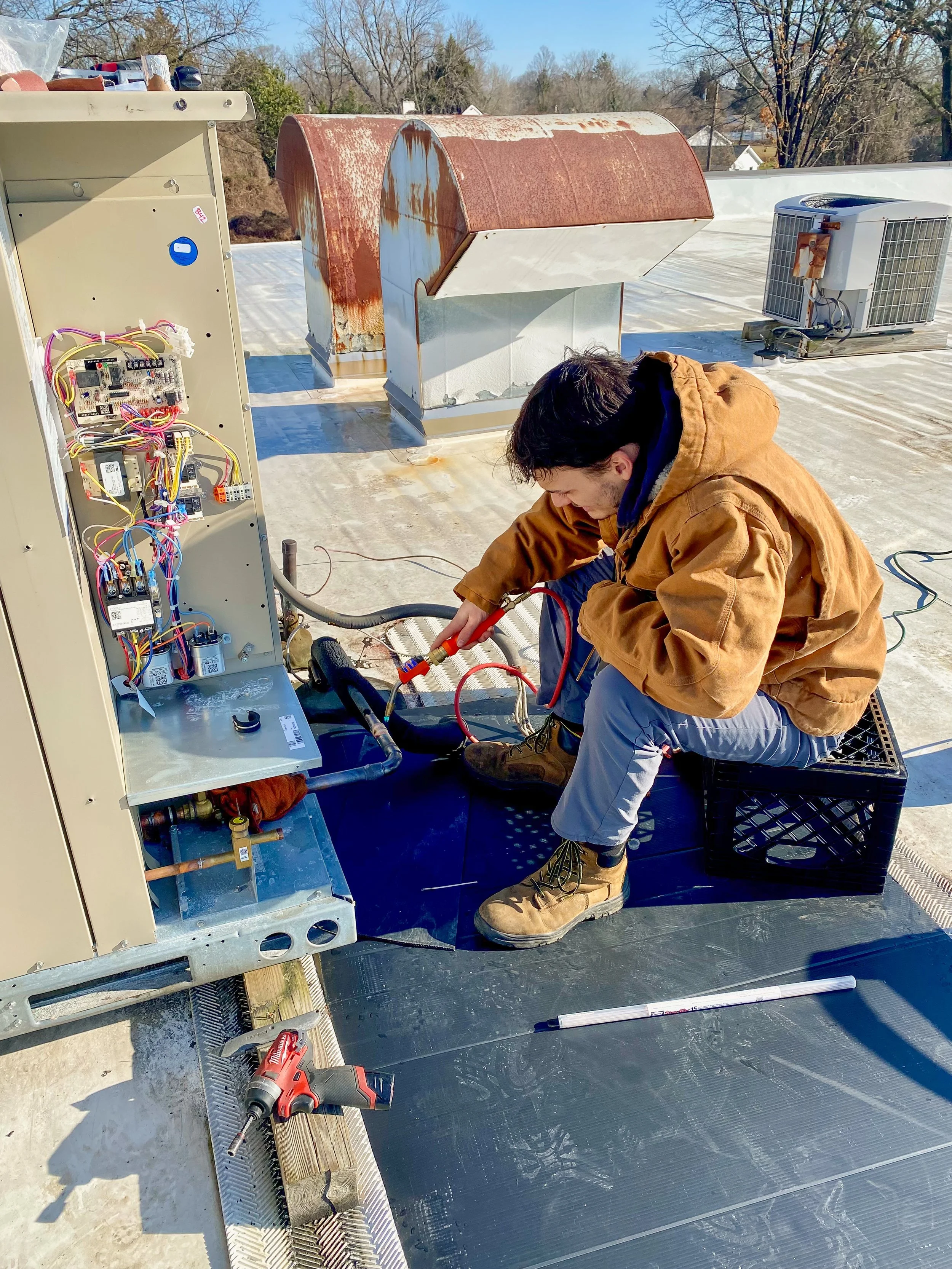 HVAC technician servicing the electrical panel of a commercial rooftop unit
