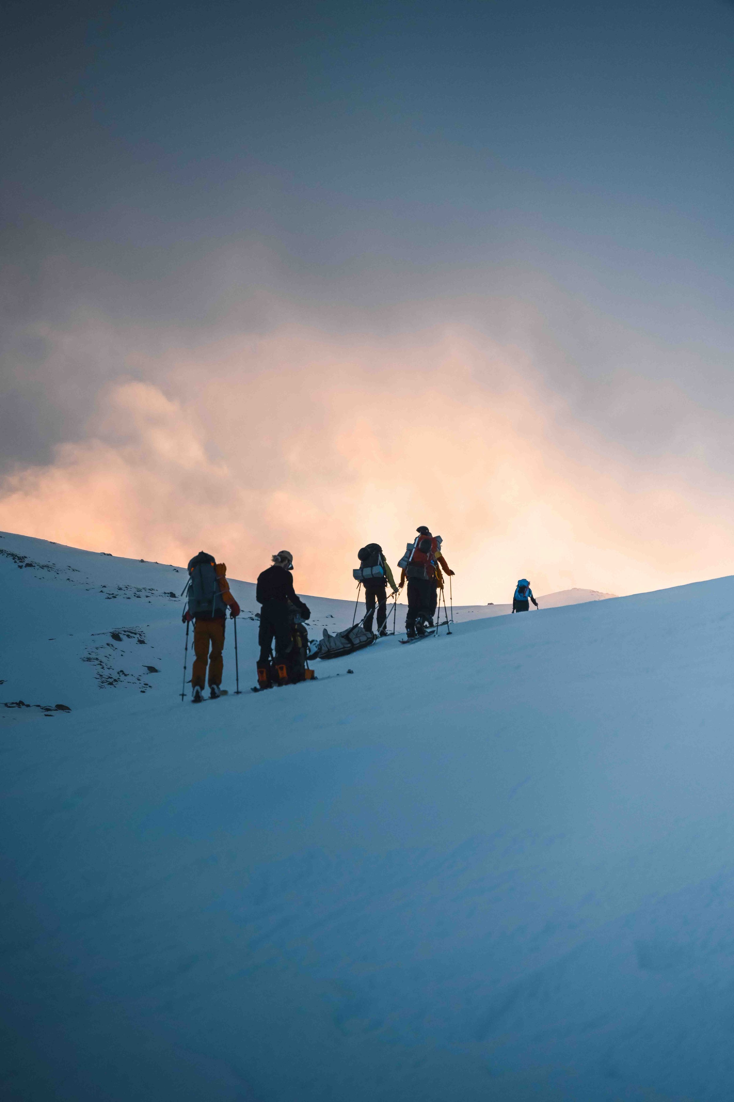The Mavens haul sleds and lug heavy backpacks on their way to camp out at the main range. The weather is rolling in. Photographer: Leah Foster