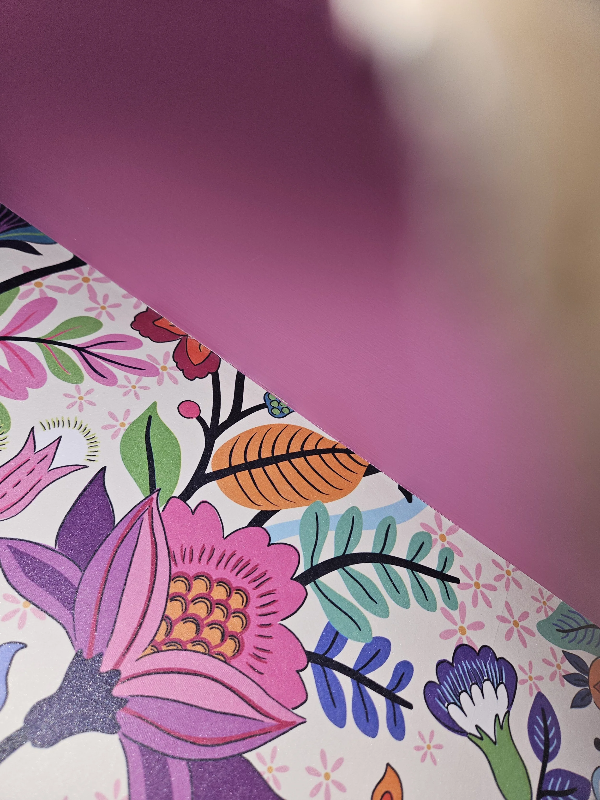 Close-up of a colorful floral patterned sheet partially covered by a pink surface.