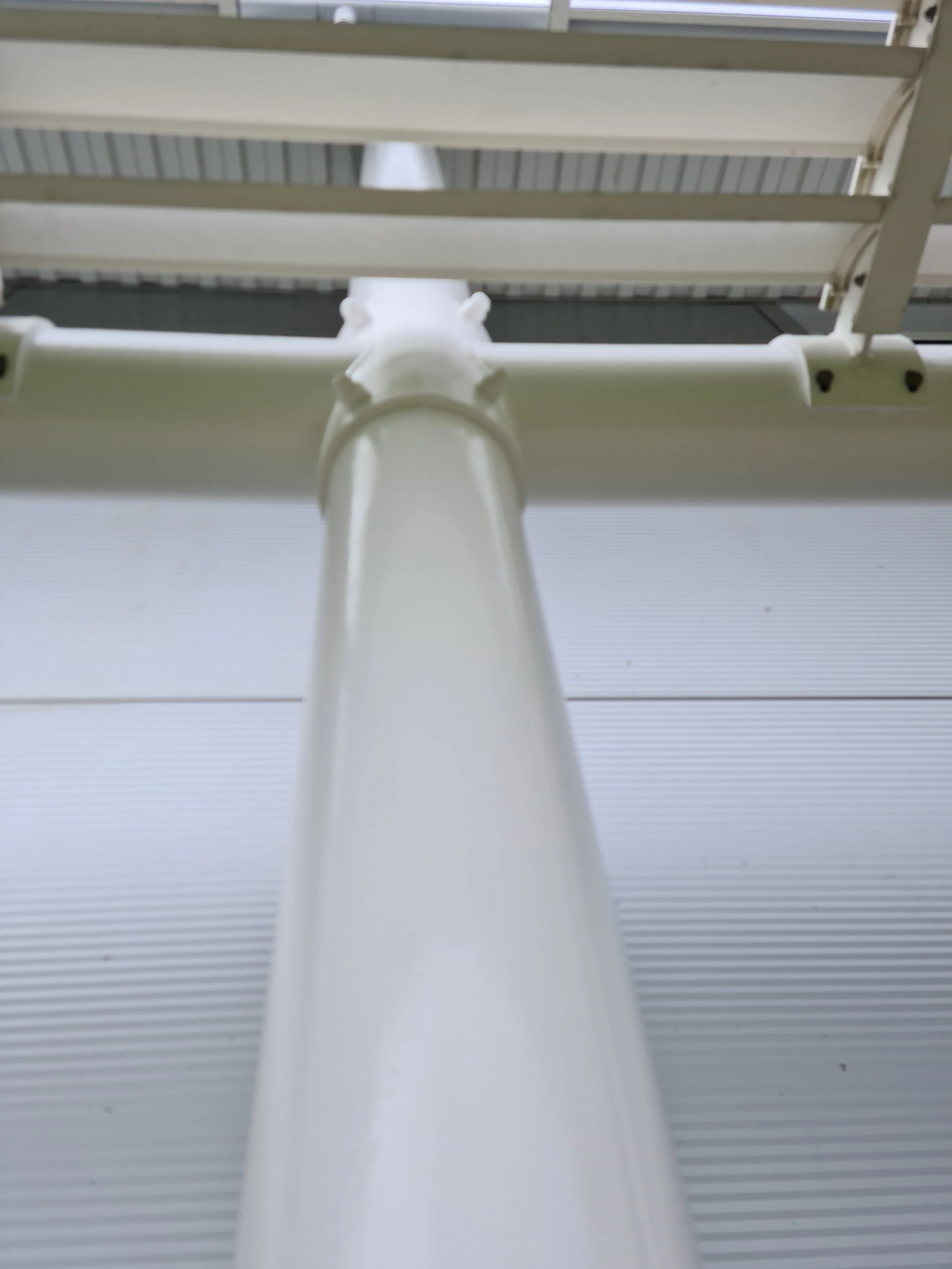 Close-up of a white metal pole and furniture from below, with part of the ceiling visible in the background.