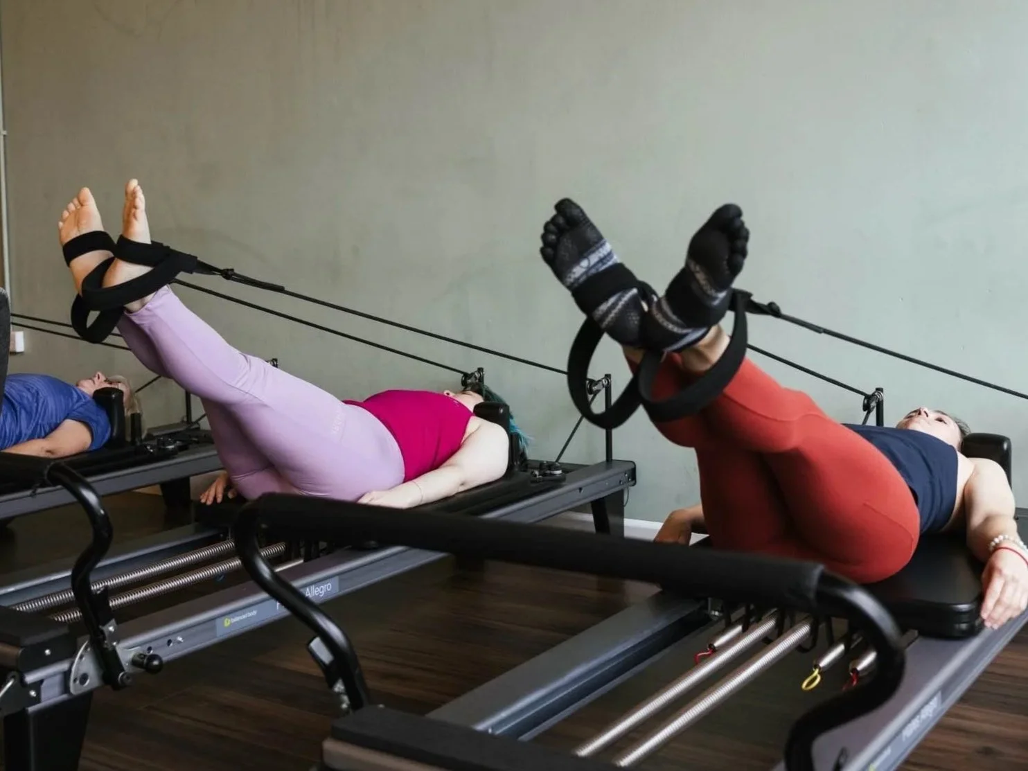 Reformer Pilates Align mixed level class of two clients on the reformer, feet in straps