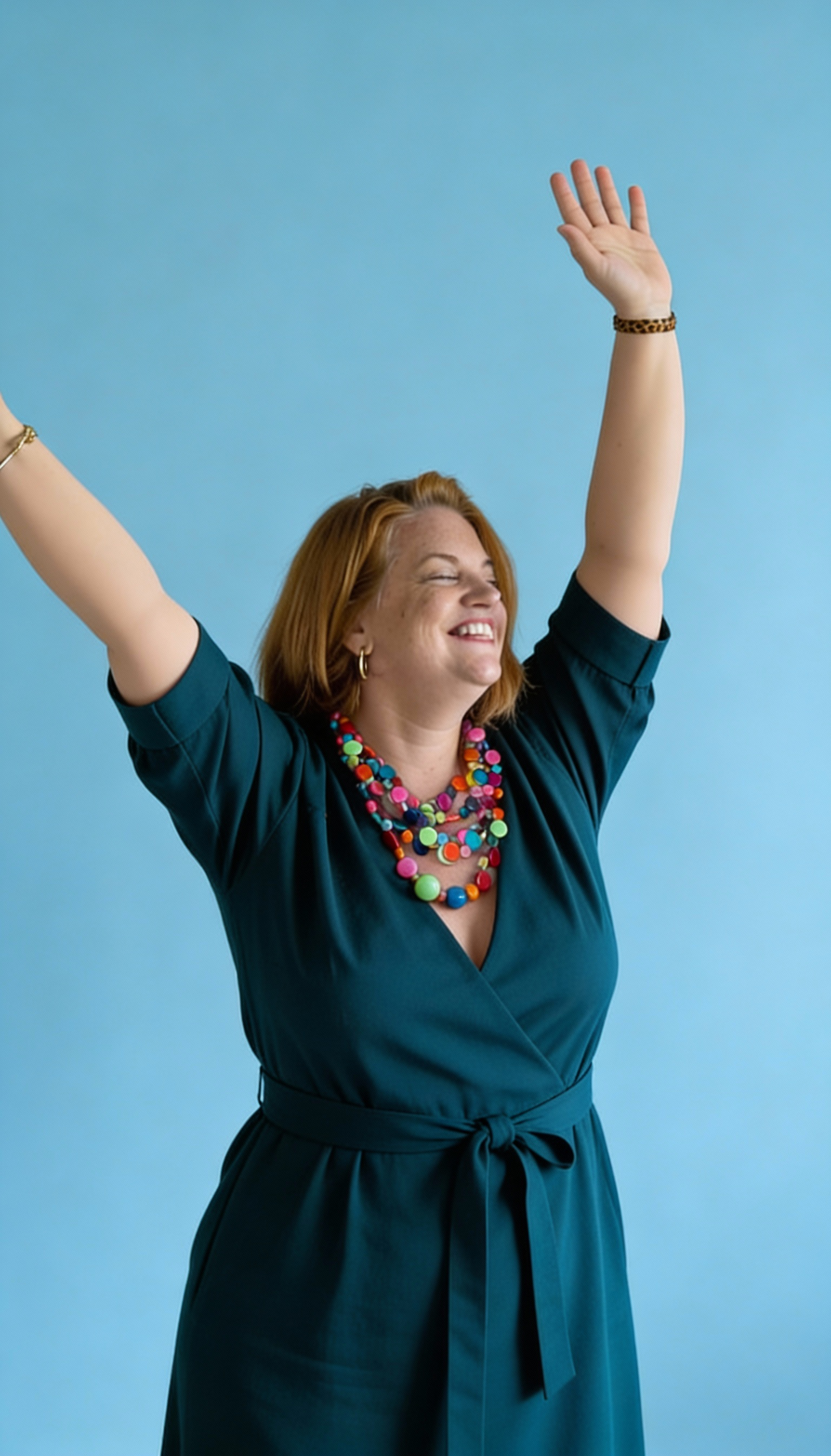 Confident woman wearing a bold colourful necklace with arms raised