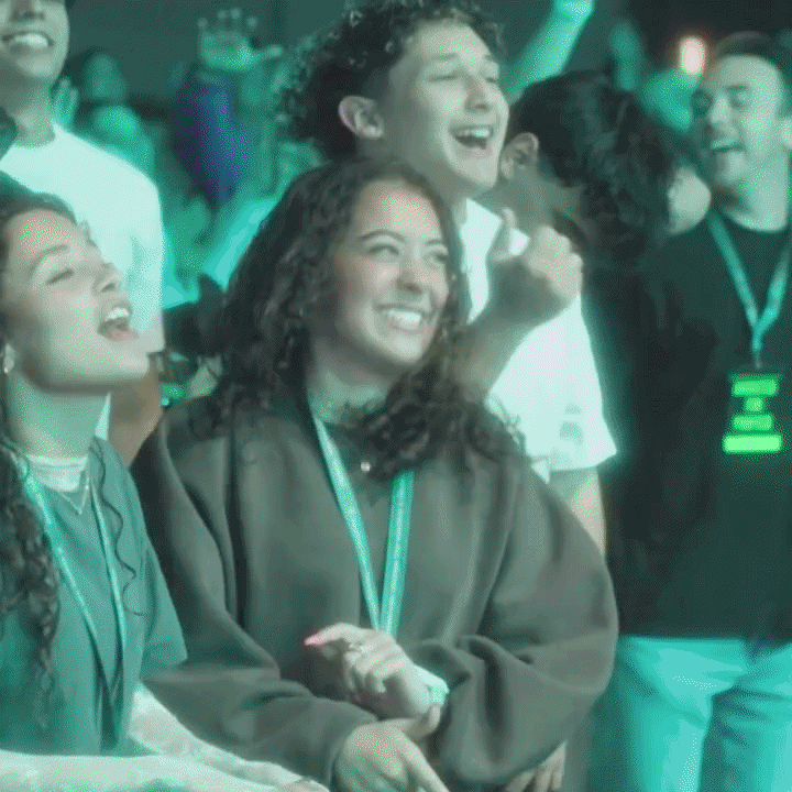 Group of young adults at a lively event, smiling and laughing, wearing conference lanyards.