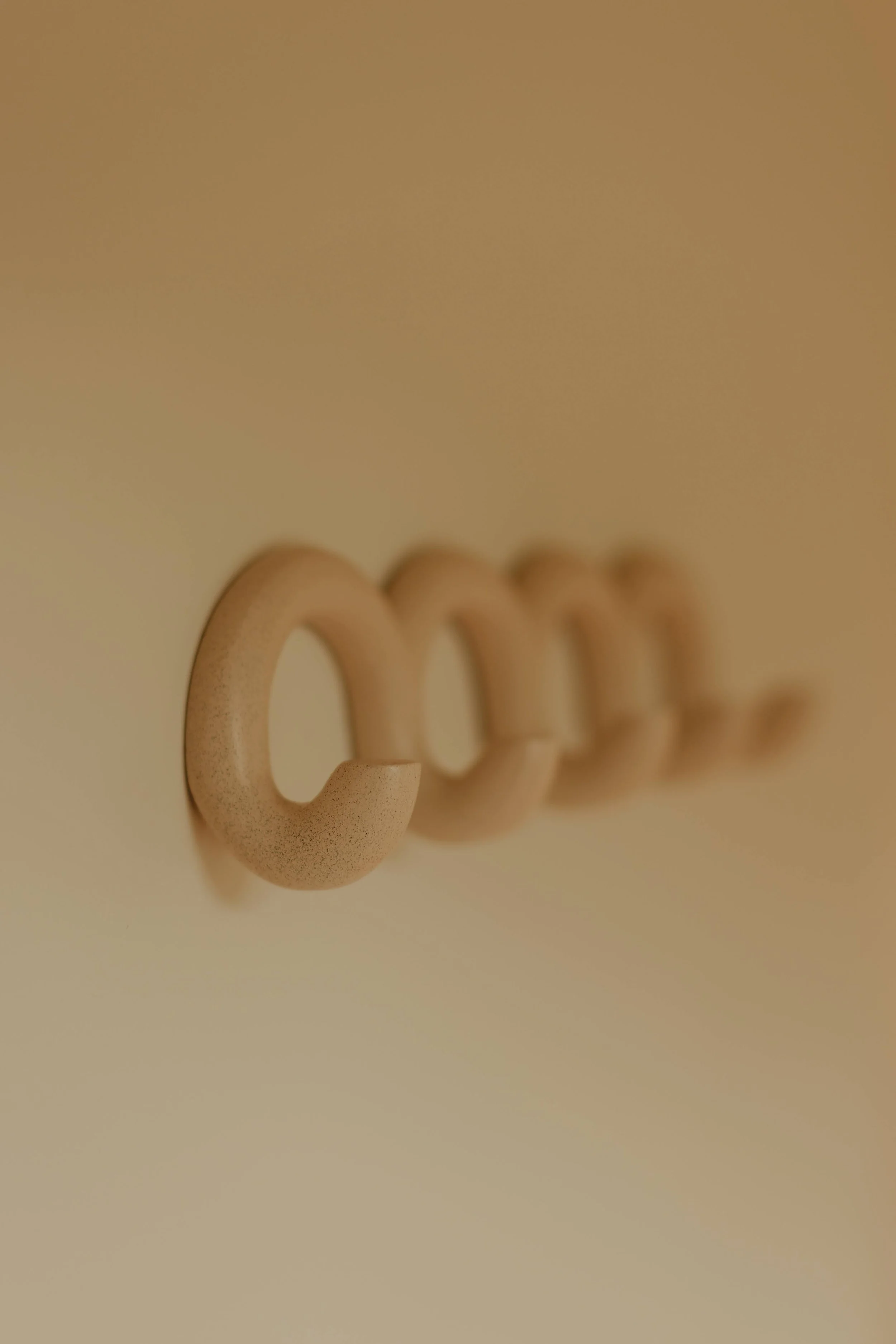 Close-up of beige plastic hooks mounted on a wall, with the focus on the front hook and the rest gradually blurred in the background.
