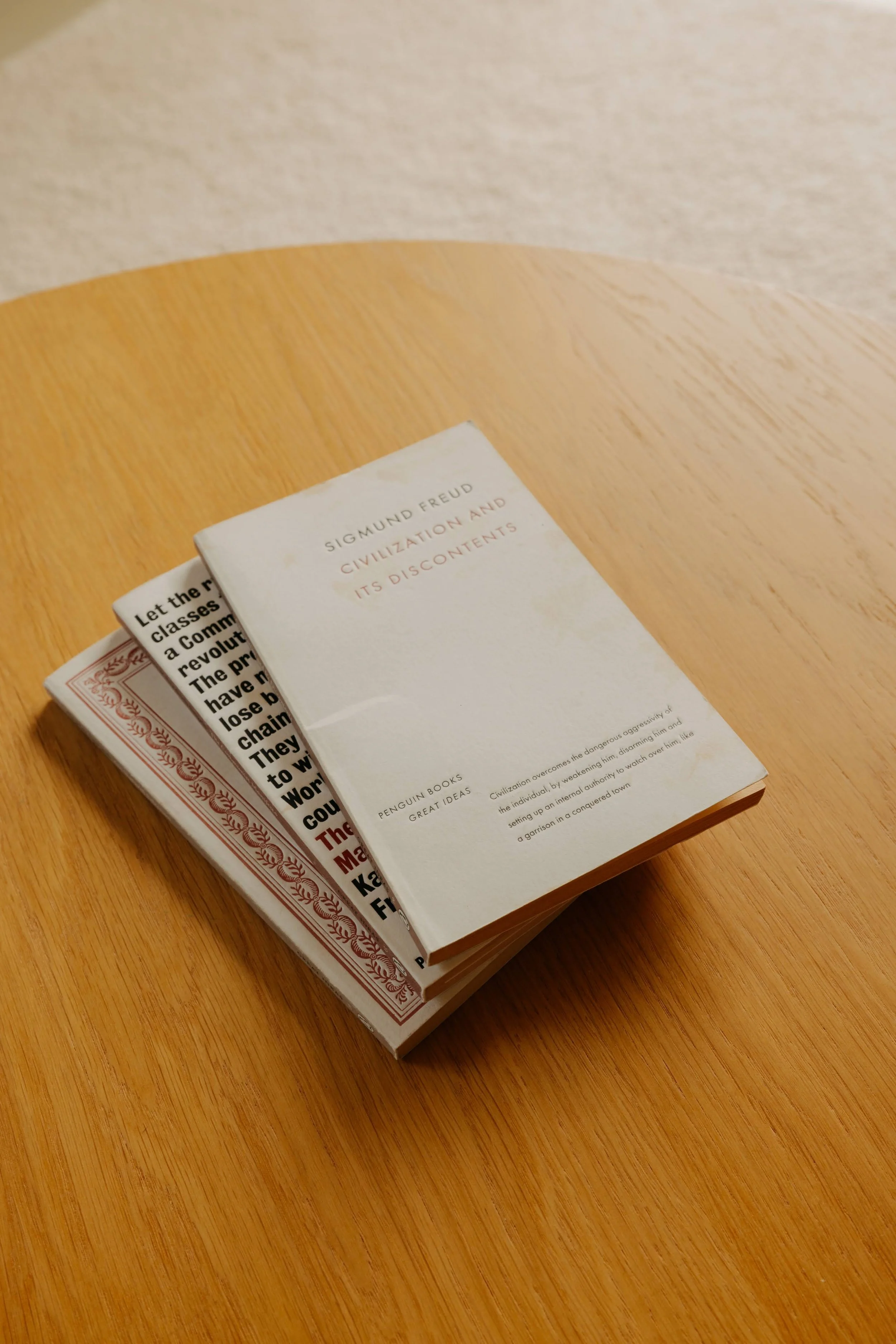 A book titled "Civilization and Its Discontents" by Sigmund Freud resting on top of another book on a wooden table.