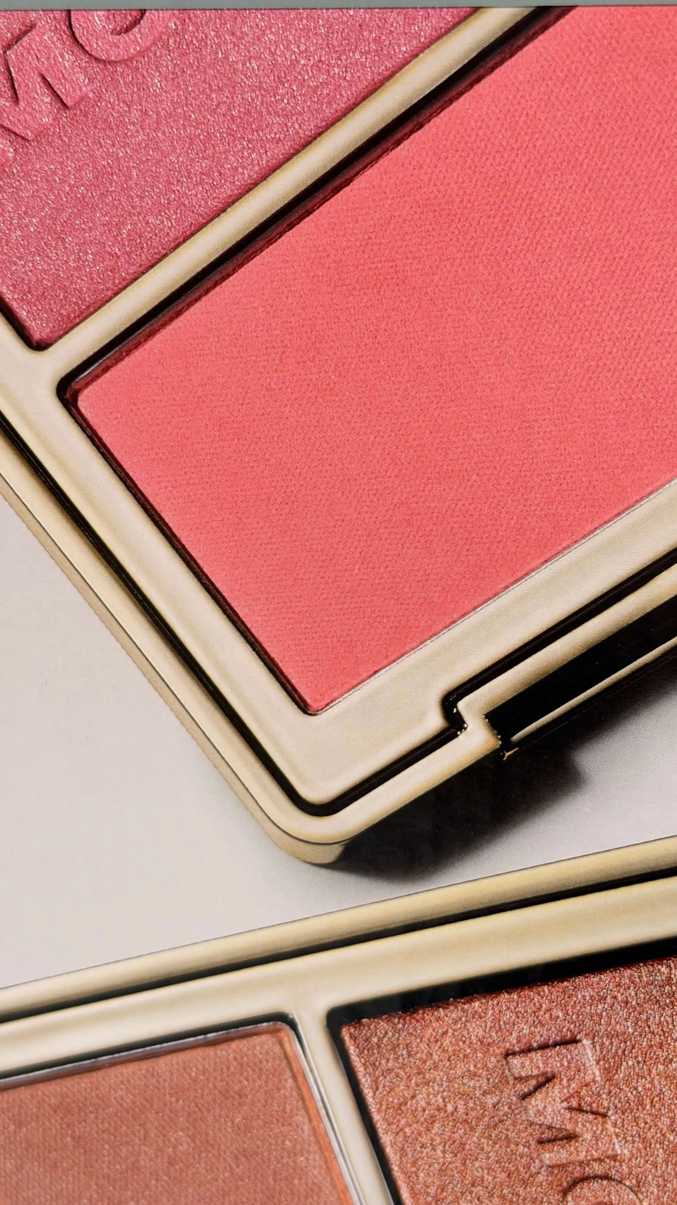 Close-up of pink and peach makeup blush palettes with textured finishes.