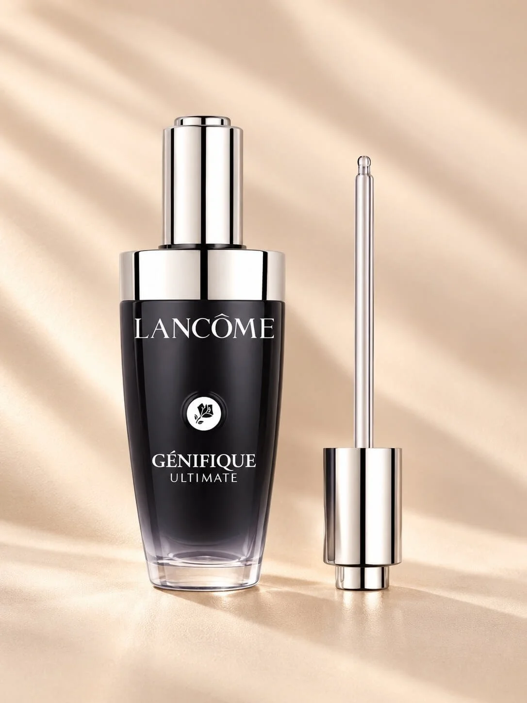 A bottle of Lancôme Génifique Ultimate serum with its dropper beside it, set against a beige satin background.