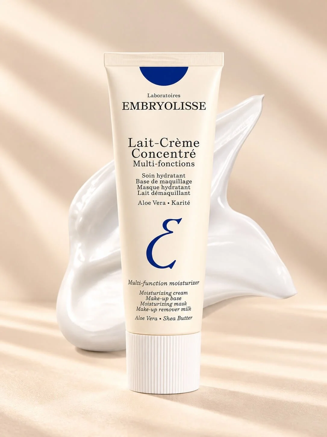 A tube of Embryolisse Lait-Crème Concentré moisturizing cream featuring text and logo, with a dollop of white cream and a background with soft beige tones.