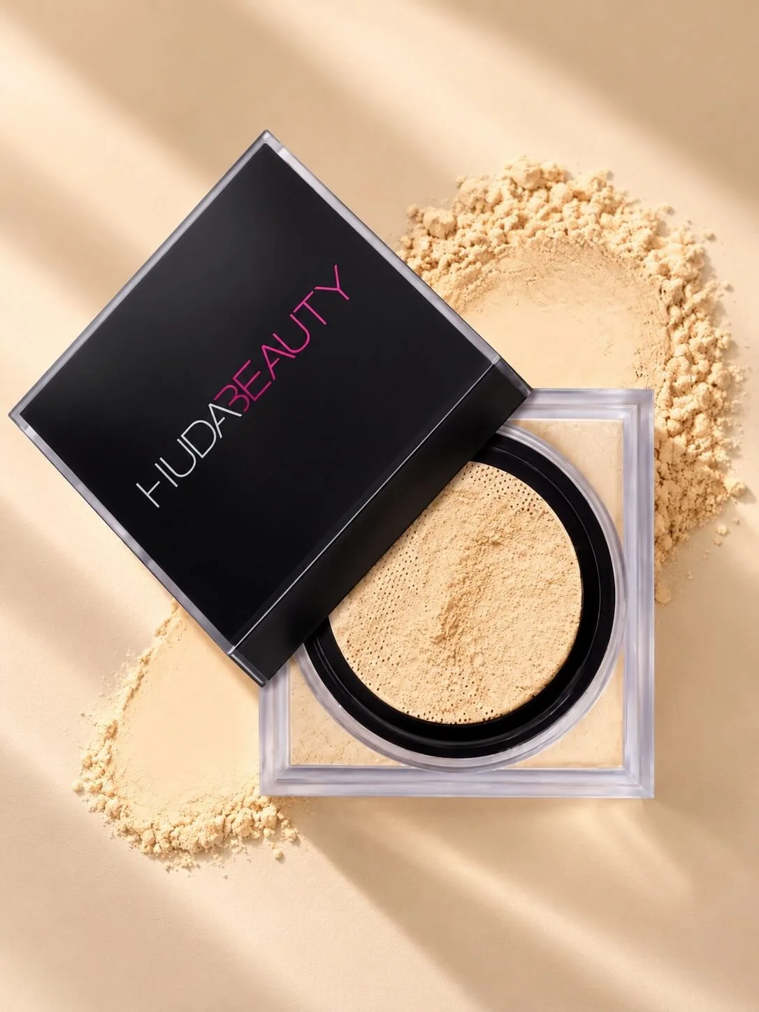 Open container of beige face powder with spilled powder on a light-colored surface.