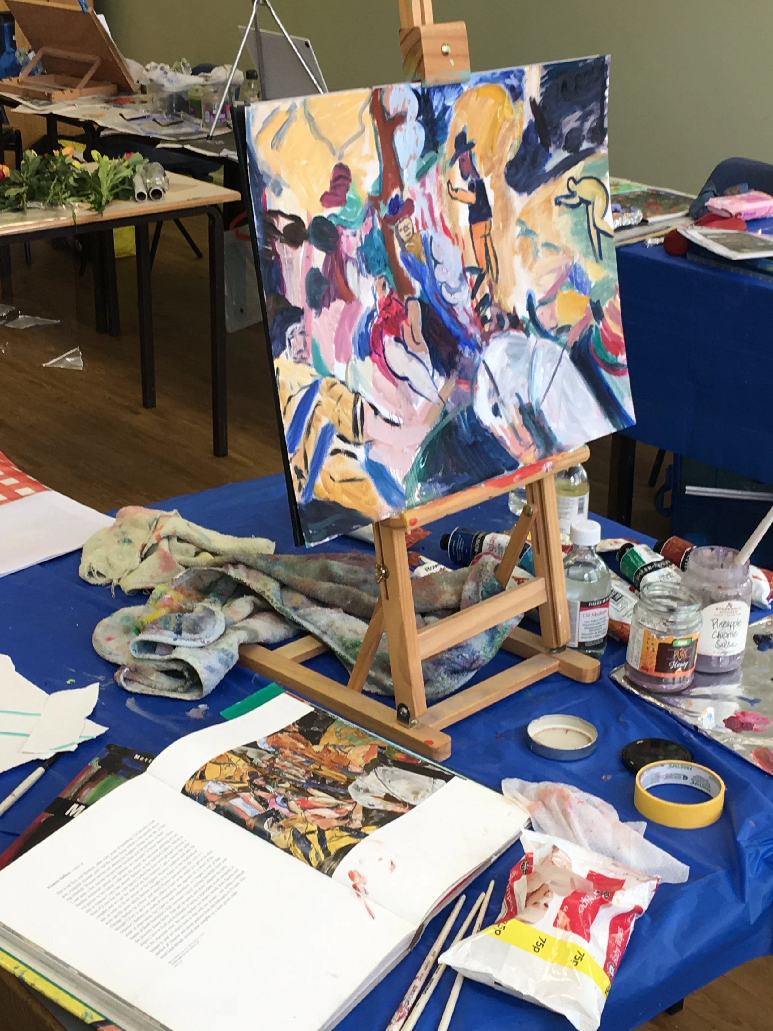 Painters studio table with oil paints, easel and reference books