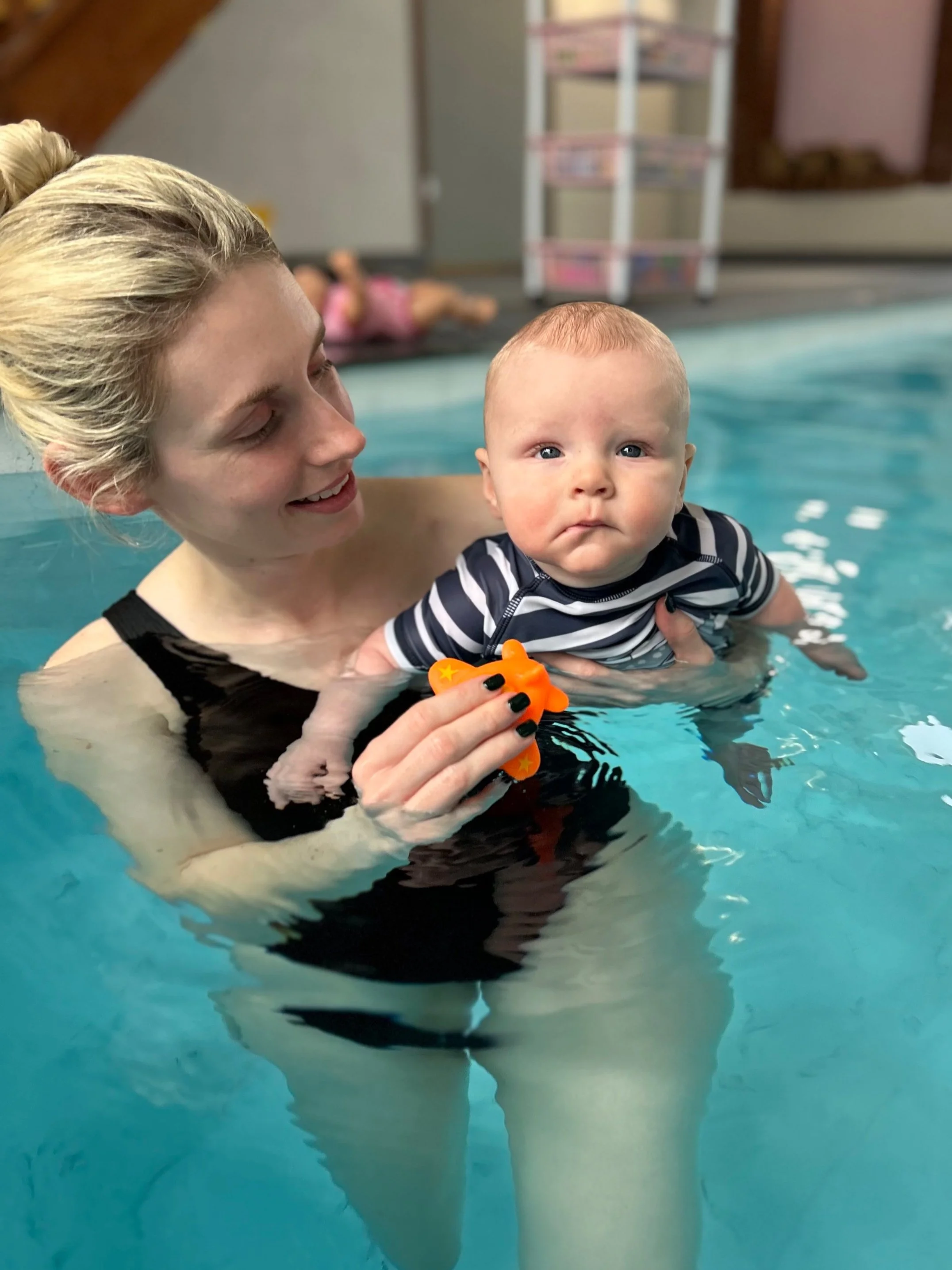 Baby swimming lessons: a parent holds their smiling baby in the pool during a baby swimming lesson