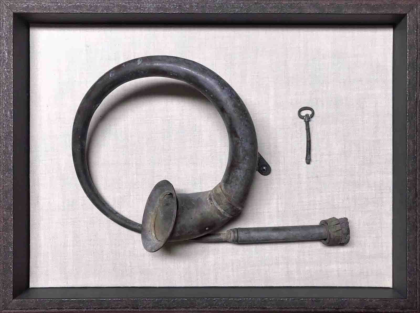 Antique horn, mounted on hand wrapped linen backing in wrought iron float frame.