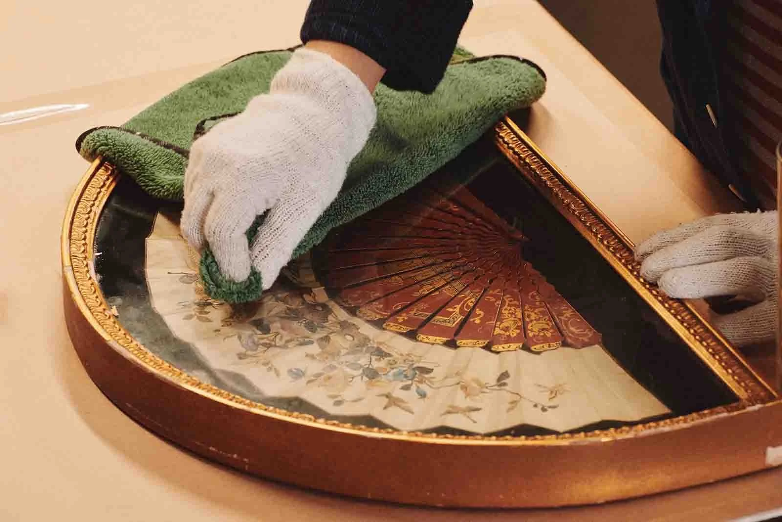 An antique embroidered chinese fan, mounted on velvet fabric and framed in a semi-circular gold gilded frame. The Frame is being cleaned and restored at Mangoe Arts, in Nashville, TN.