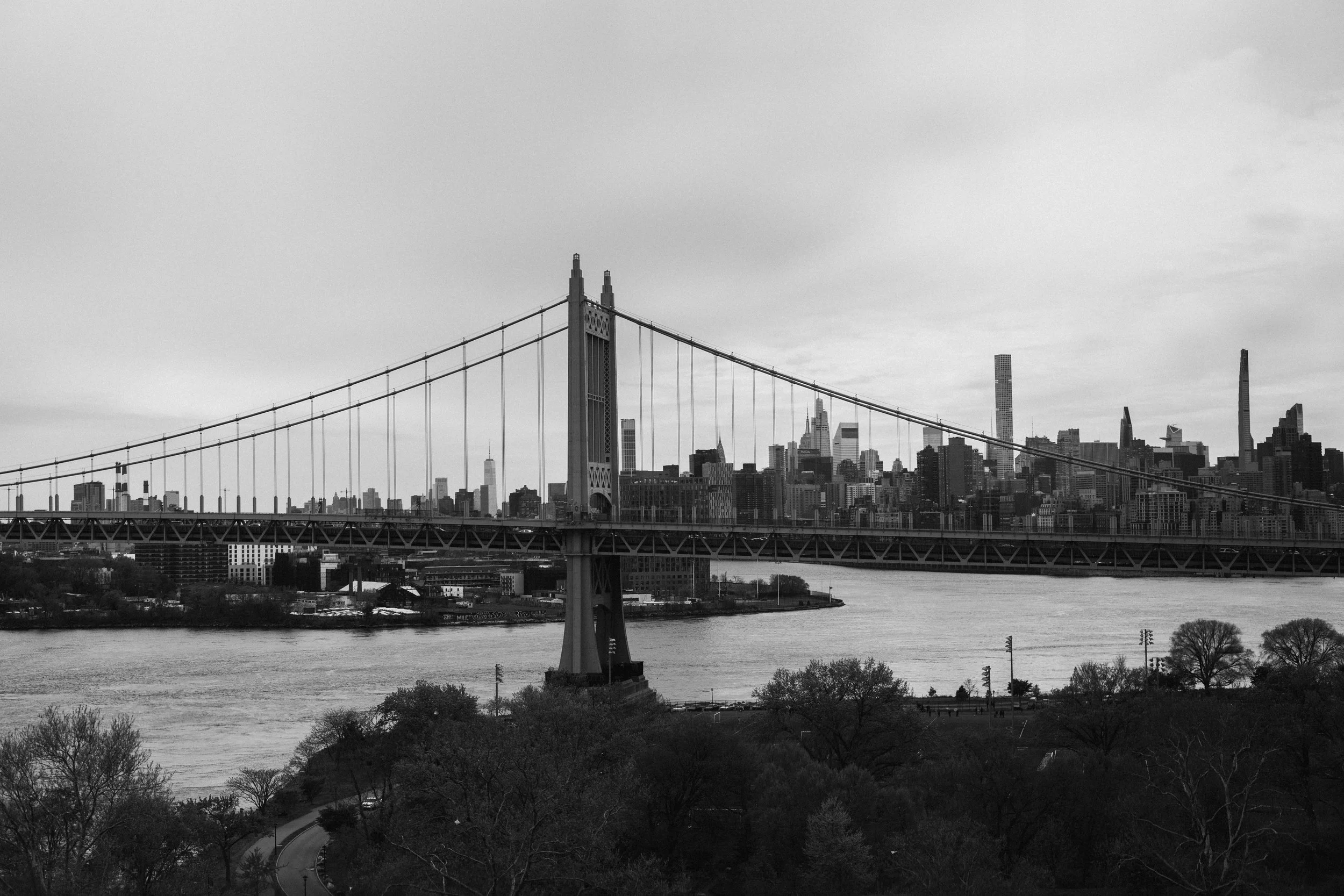 Black and white photo of the Brooklyn Bridge with Manhattan skyline in the background.