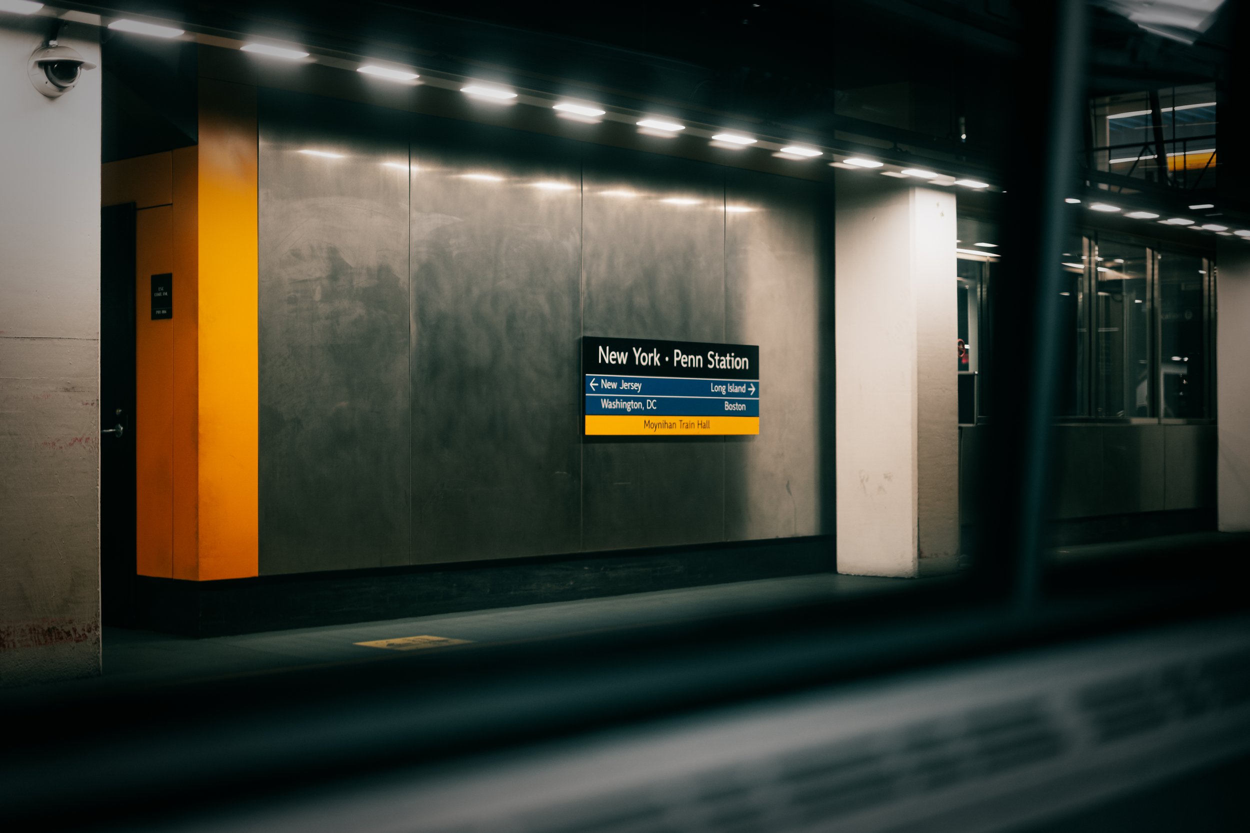 Sign at New York Penn Station indicating directions for trains to New Jersey, Washington DC, Long Island, and Boston, with the Moynihan Train Hall entrance.