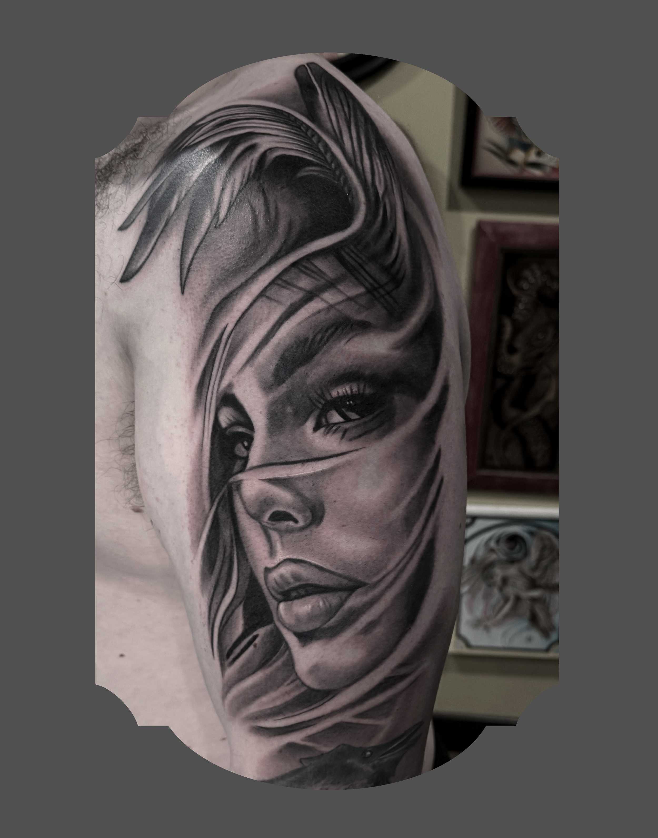 Close-up of a black and gray tattoo of a woman's face on a person's shoulder.