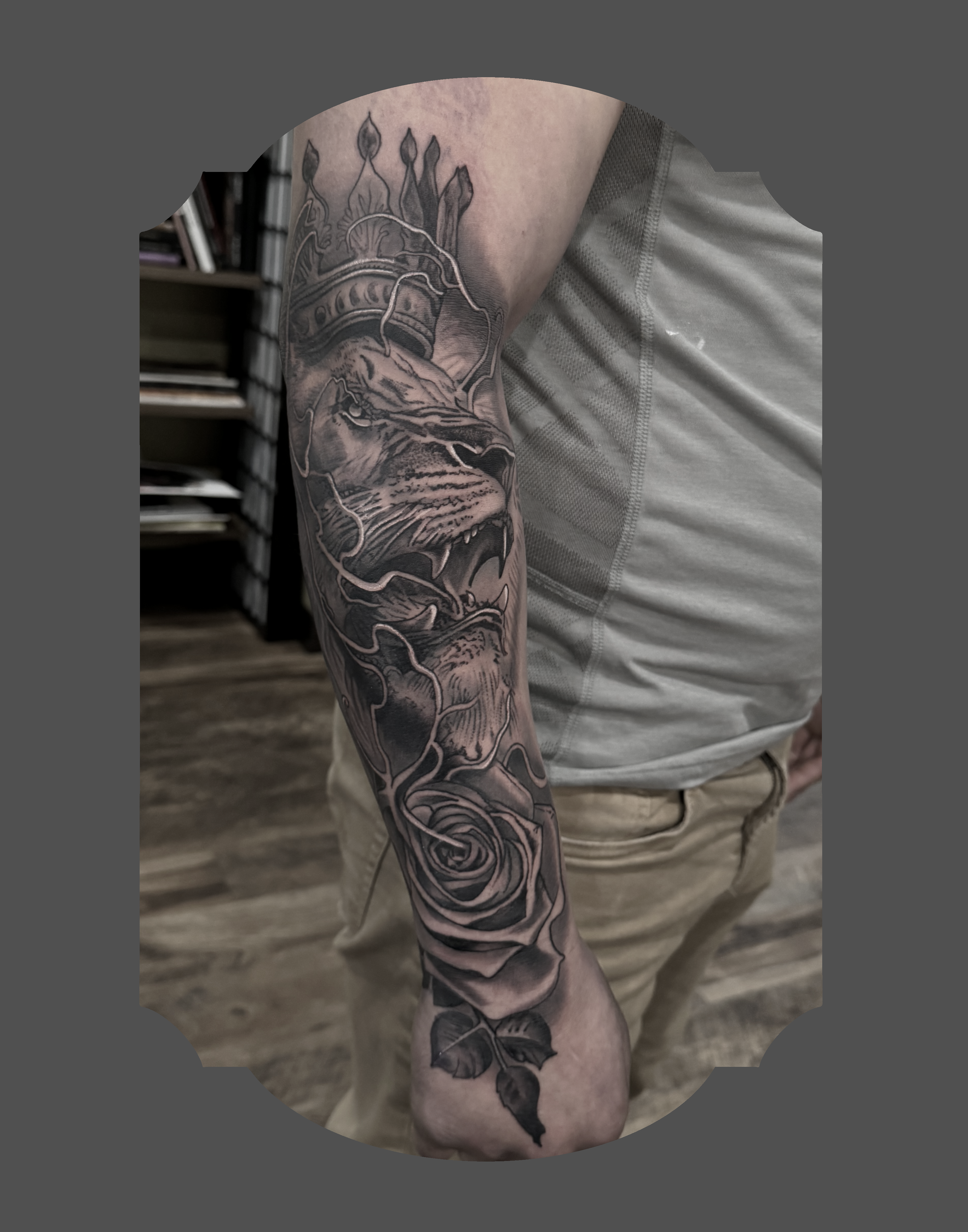 Tattoo of a lion's face with a rose at its base on a person's arm.