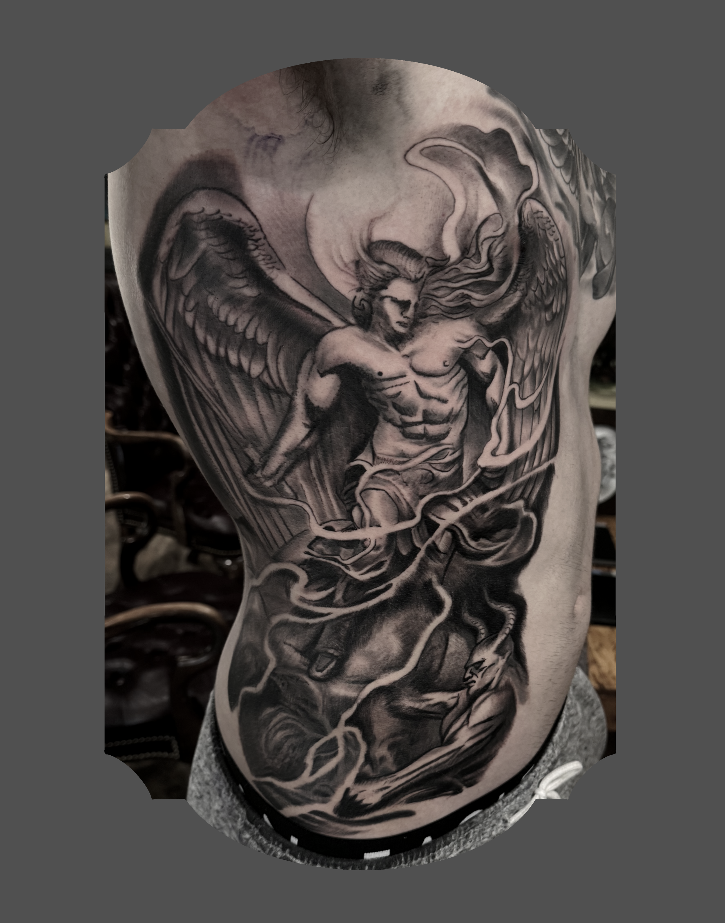Black and gray tattoo on person's chest and shoulder depicting a woman with flowing hair, angel wings, and a cloud background.