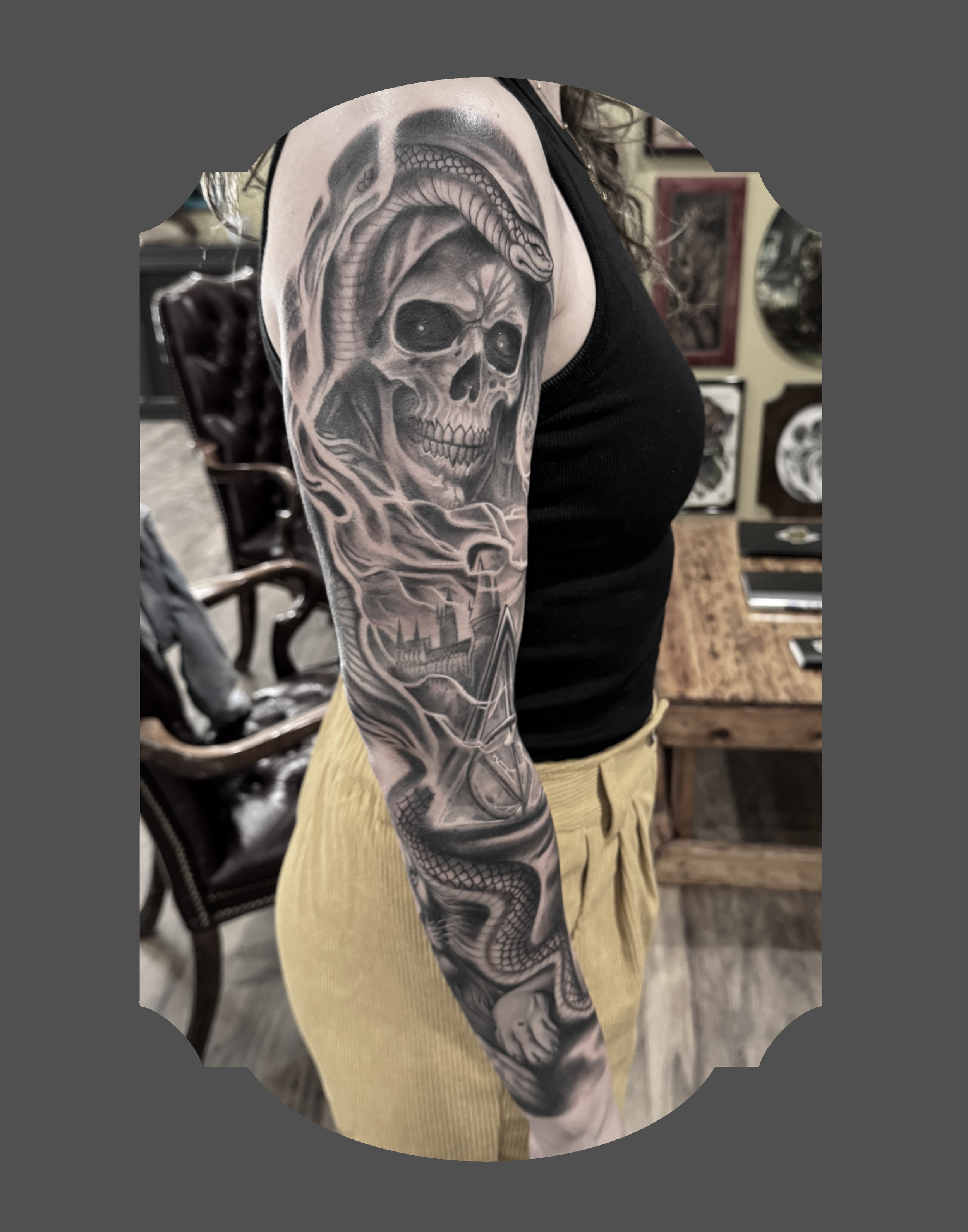 Tattoo of a skull with a snake on the upper arm.