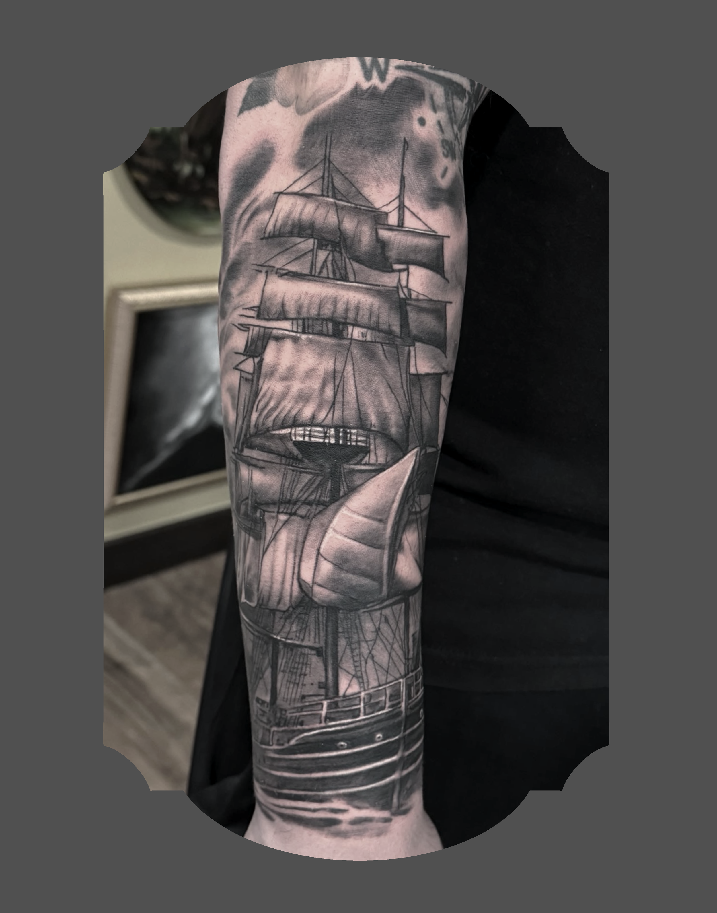 Black and gray tattoo of a sailing ship on a person's arm.
