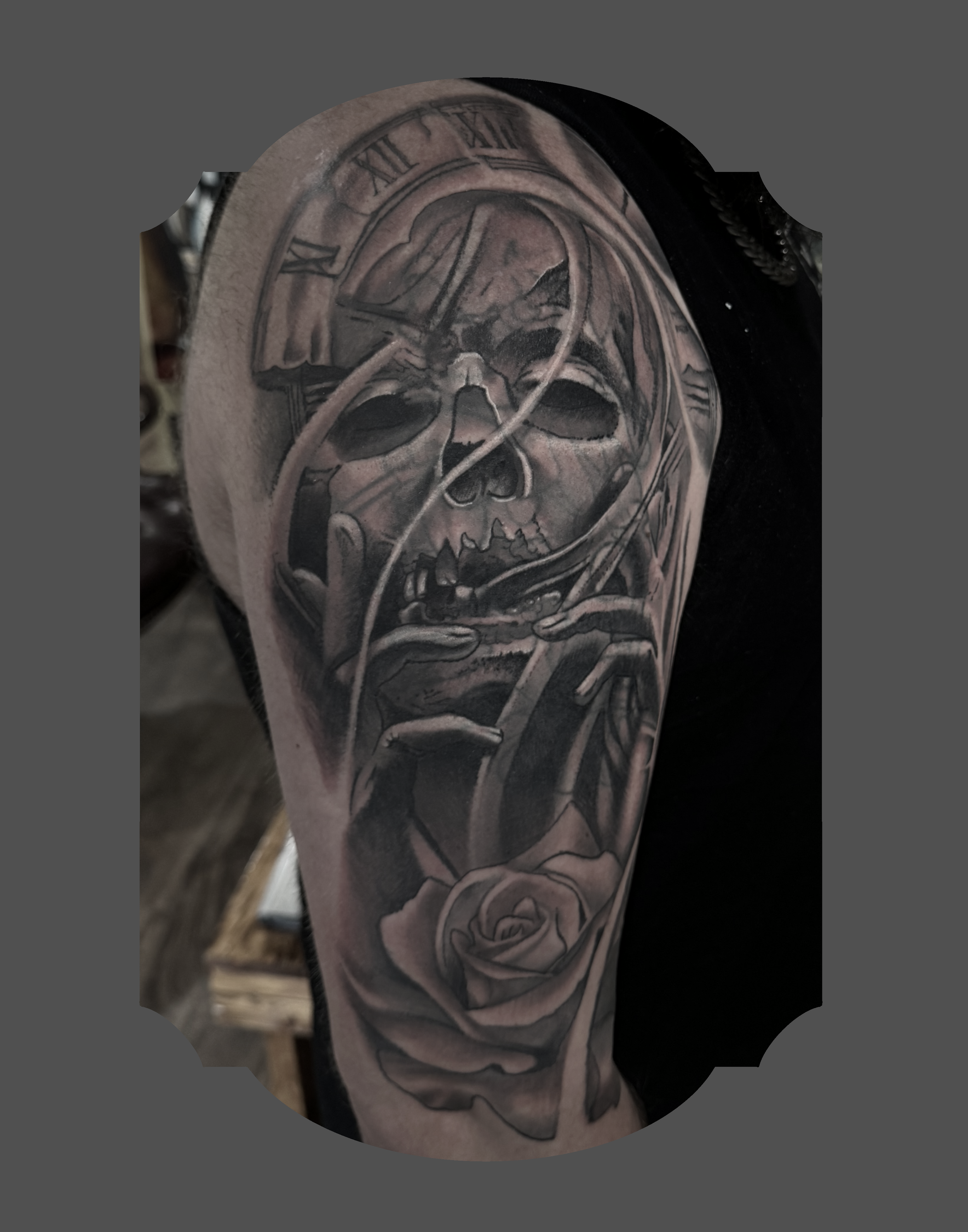 Black and grey tattoo of a human skull with a clock face and roses on the arm.
