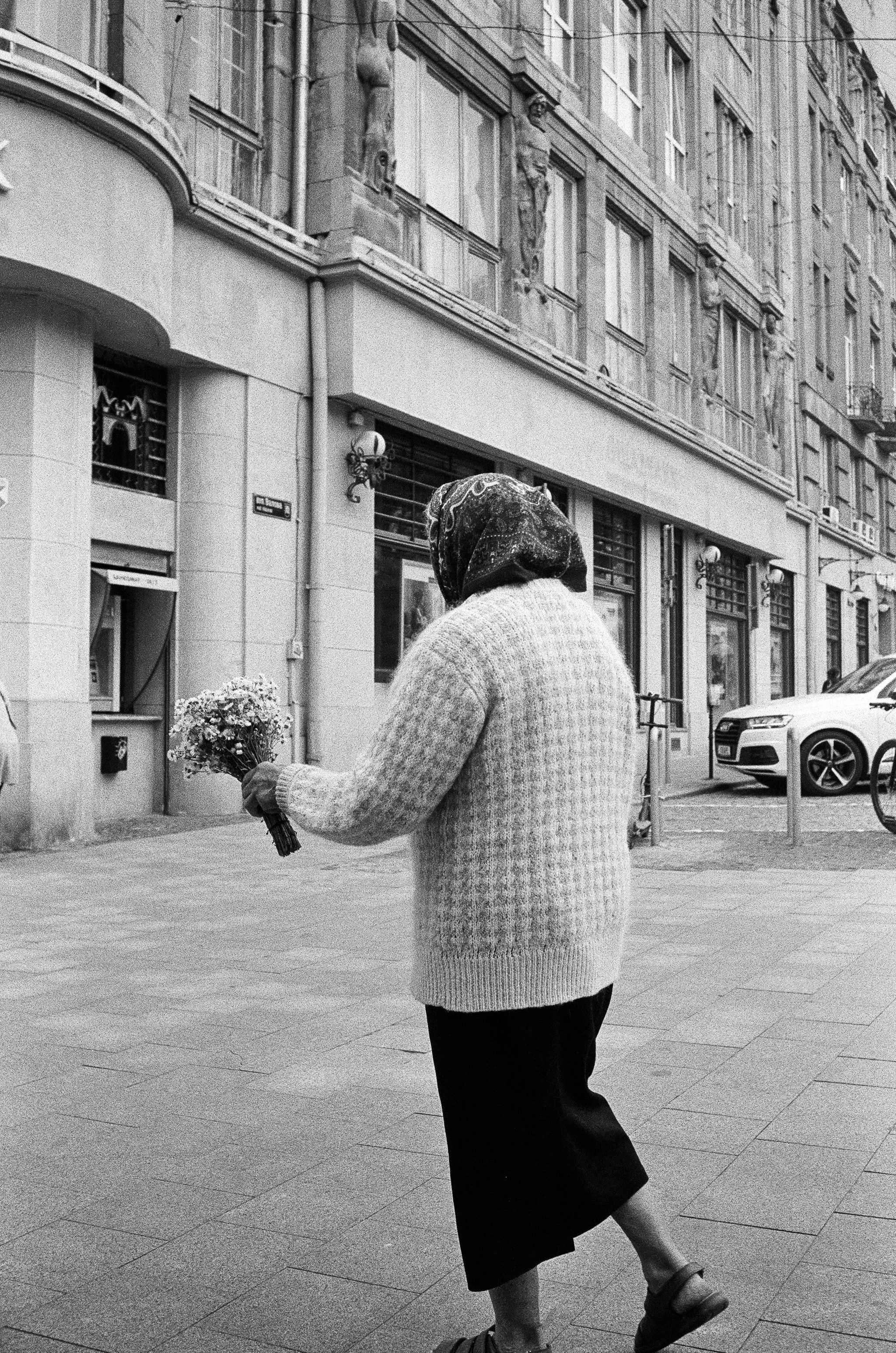 Flower vendor offering Shasta daisies to people passing by. Lviv.