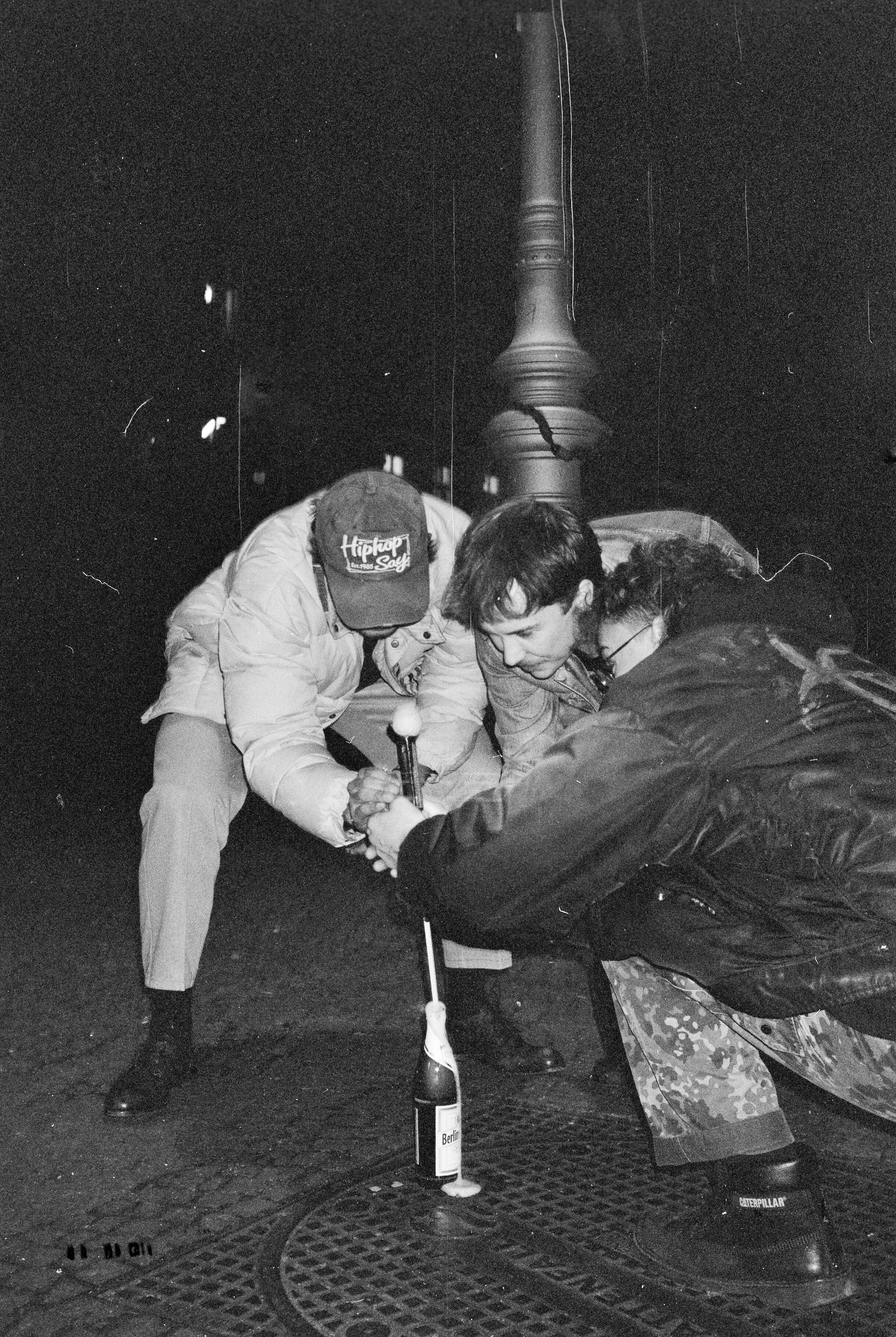 Unknown, Ari, and Anton, lighting a firework out of a bottle of beer. New Years Eve, Reichenberger Straße.