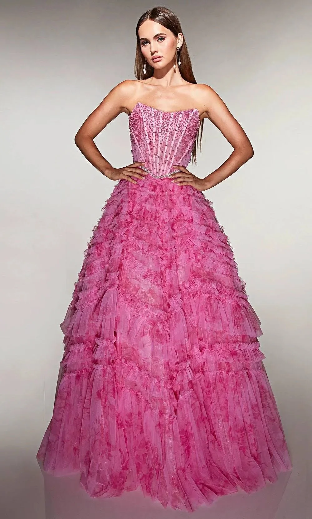 A woman in a shiny, strapless, magenta gown with a thigh-high slit poses against a dark background, with her reflection visible on the surface behind her.