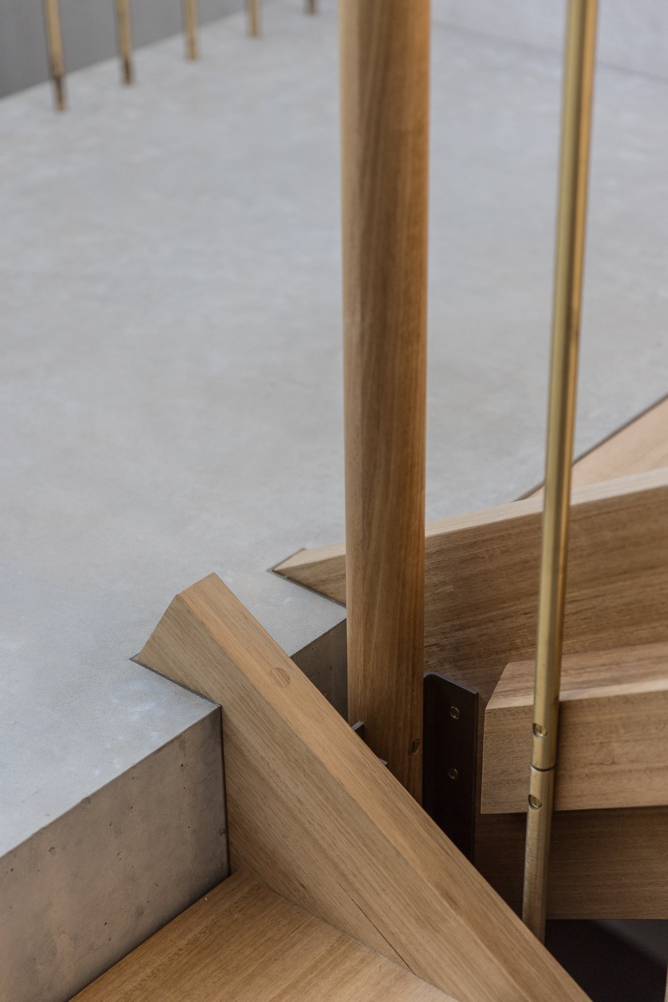 Close-up view of a modern staircase with grey concrete steps, wooden and metal handrails, and wooden steps.