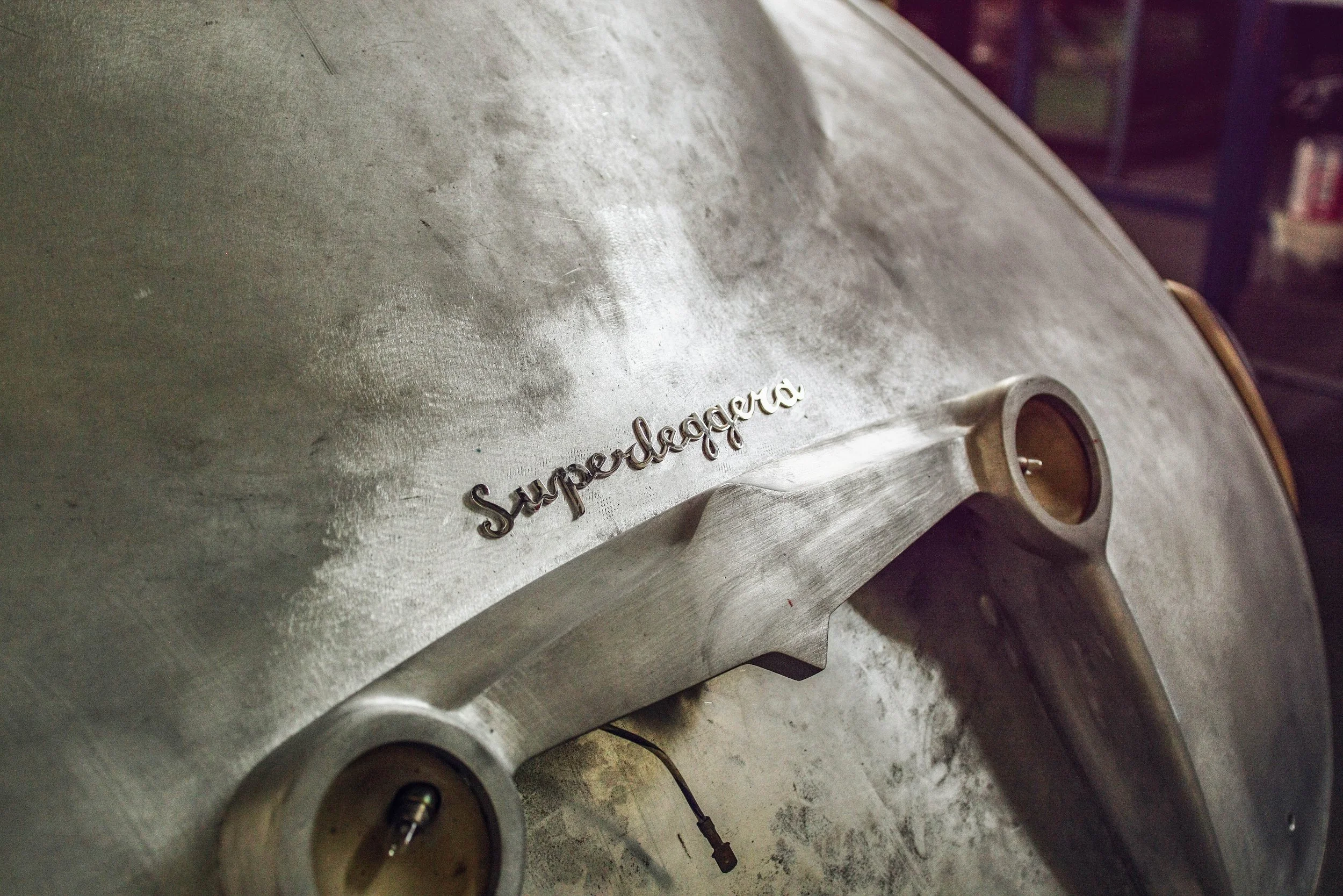 Close-up of a metallic grill with a silver handle and the word 'Superflago' in script. The surface appears slightly worn or textured.