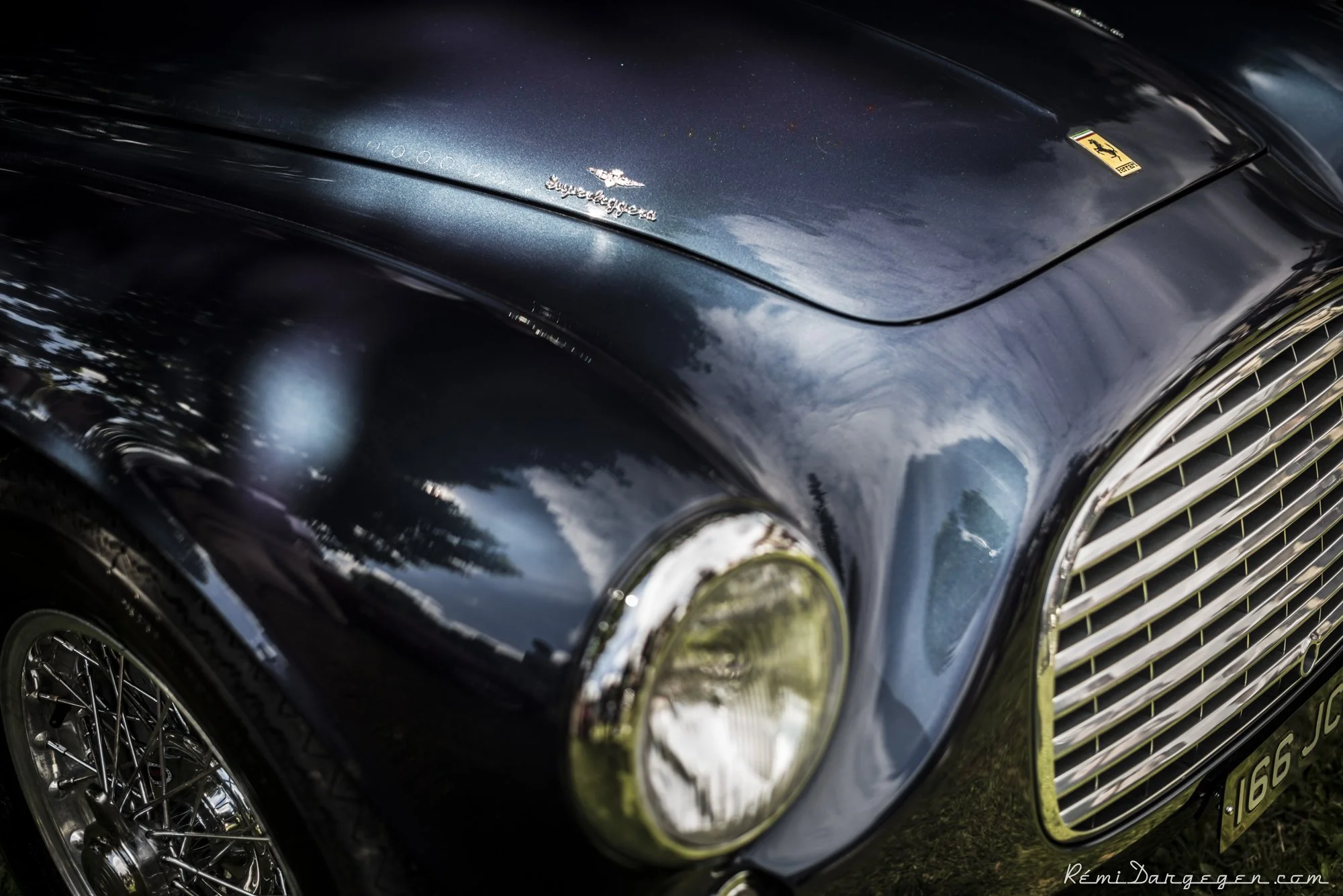 Close-up of a classic black Ferrari car with reflections on its shiny surface, showing the front grille and headlight.