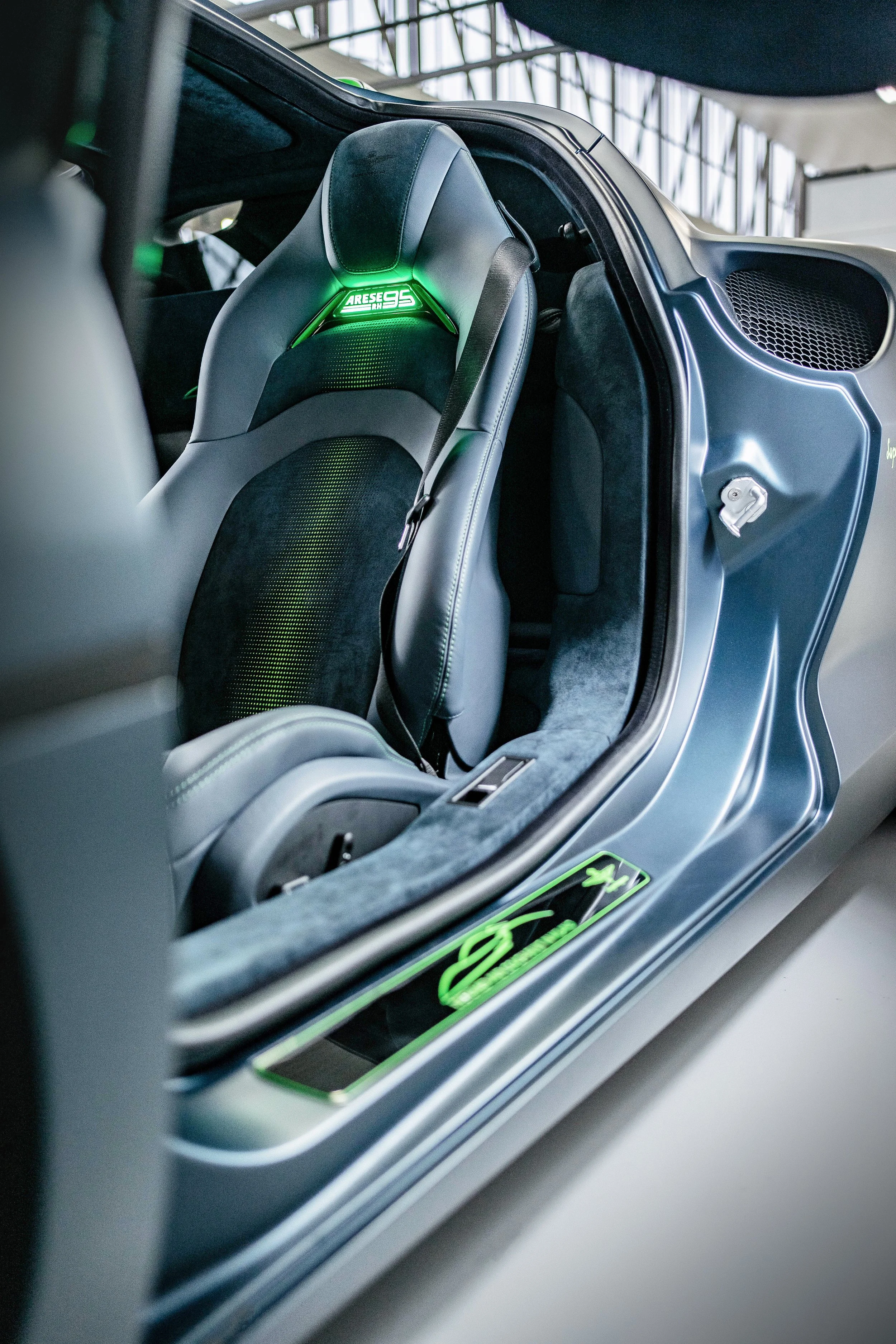 Close-up of a futuristic car interior showing a racing seat with illuminated green branding and sleek design.