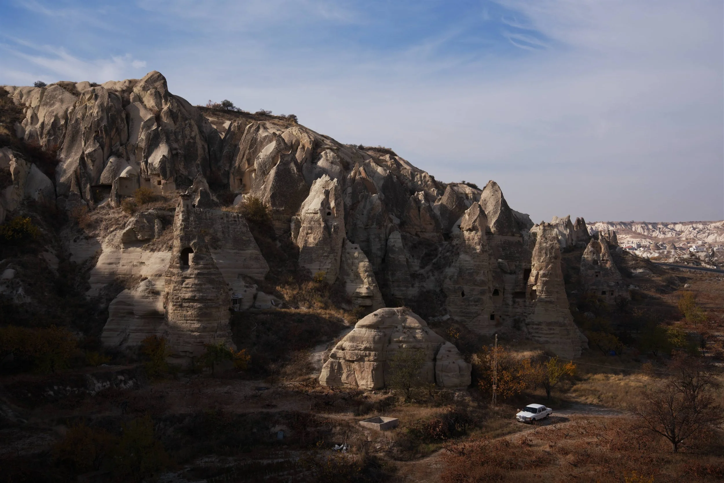Landscape photo of Zelve Valley in Goreme, Cappadocia, Turkey with fairy chimney cave houses and a vintage car.
