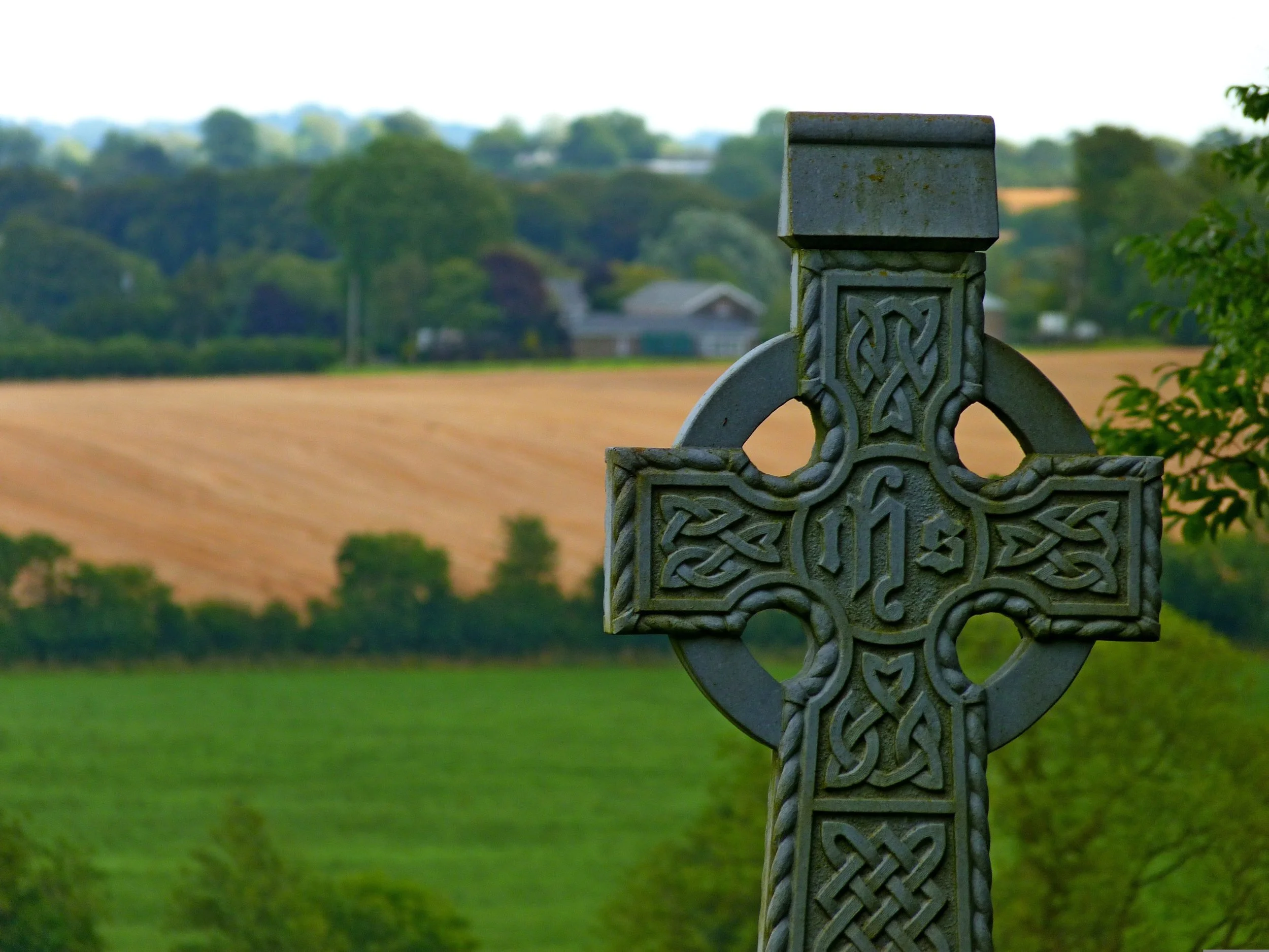 Celtic cross with rolling fields behind it