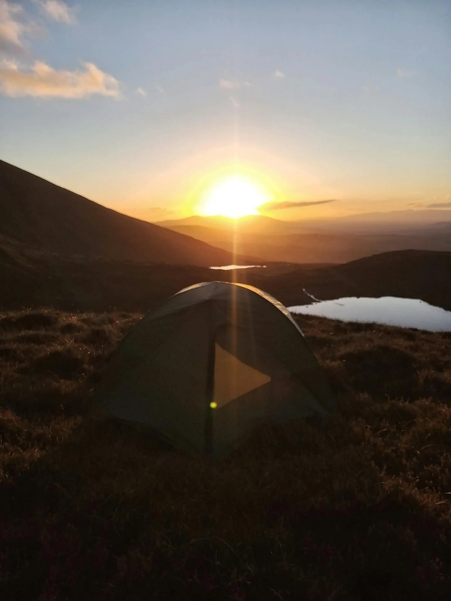 Wild camping on a hillside with sunset in the background