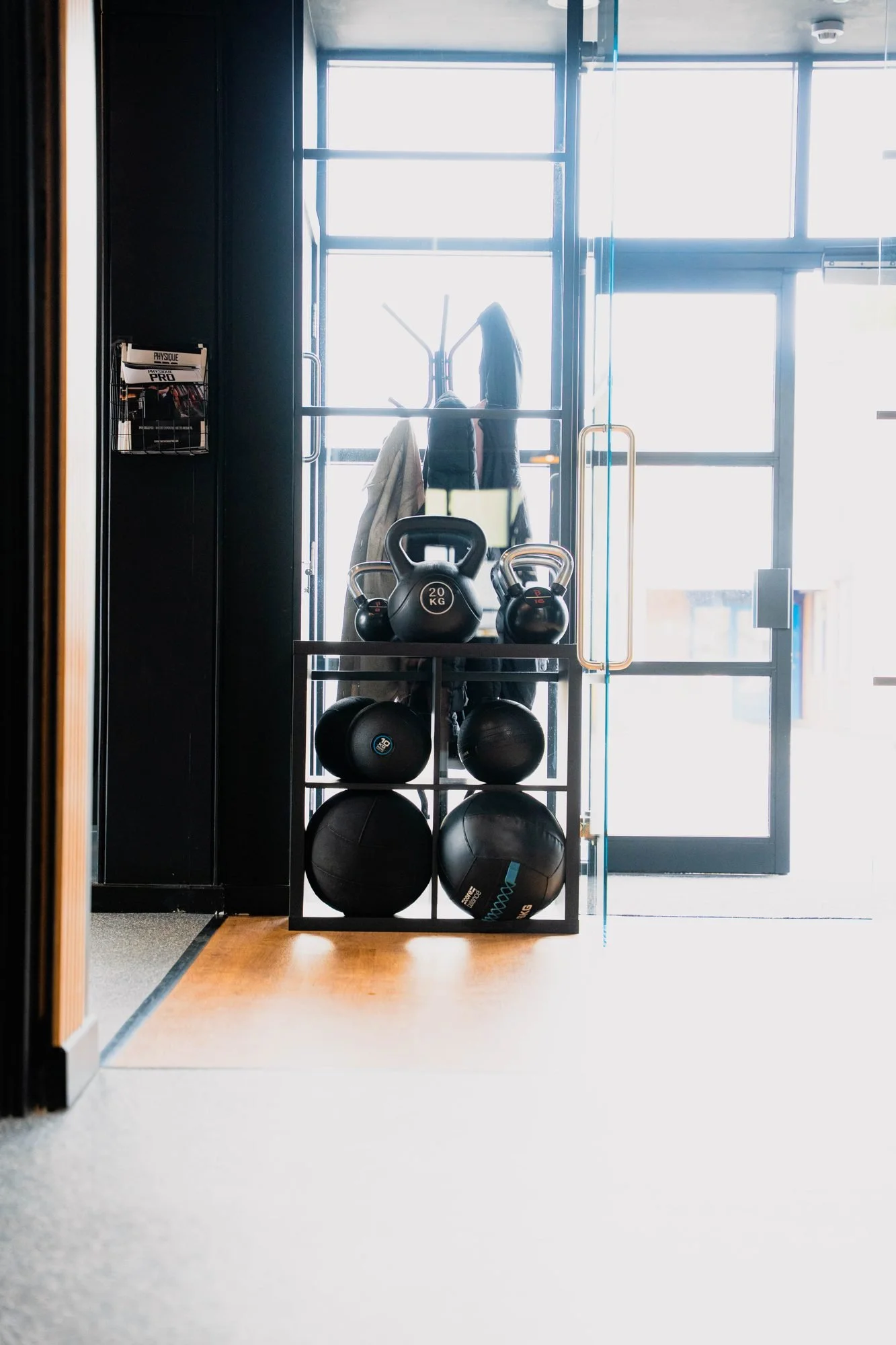 Kettlebells and medicine balls on a rack by the window at Physique Pro Gosforth