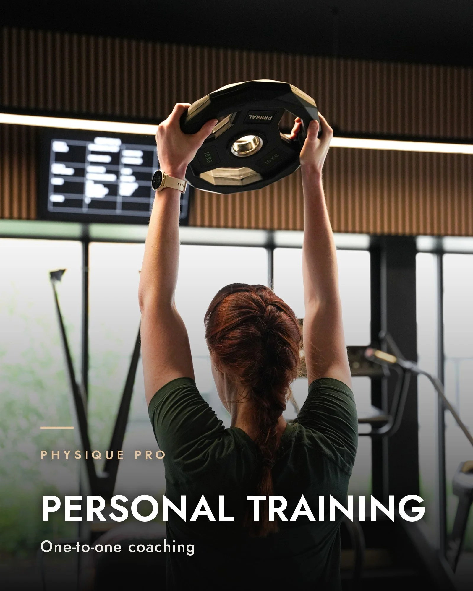 Personal training at Physique Pro in Newcastle: a member lifting a weight plate overhead in a bright gym