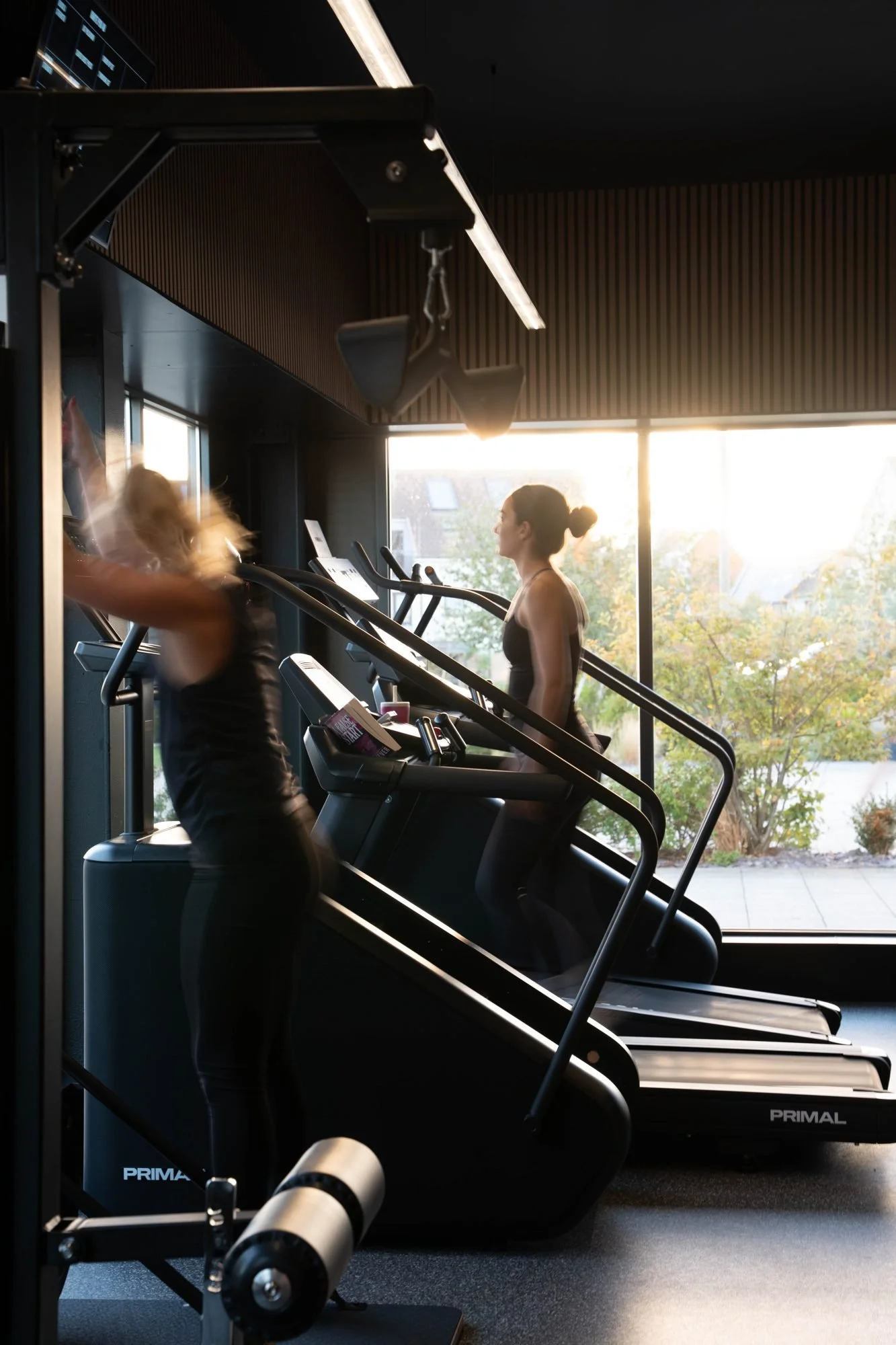 Member using a stair climber by the bright windows of the cardio area at Physique Pro Great Park