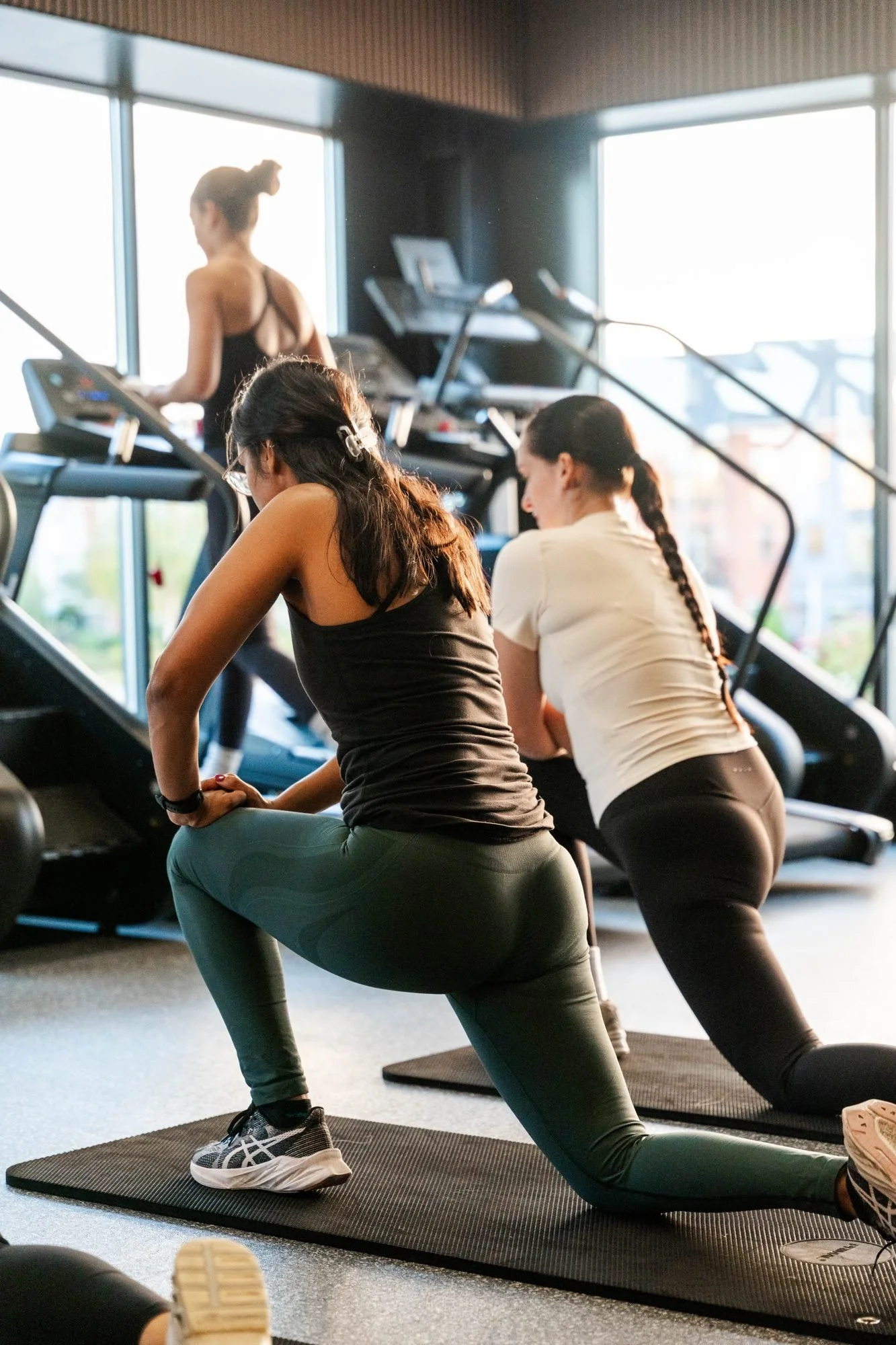 Two members doing lunges on mats during a small-group class at Physique Pro Great Park