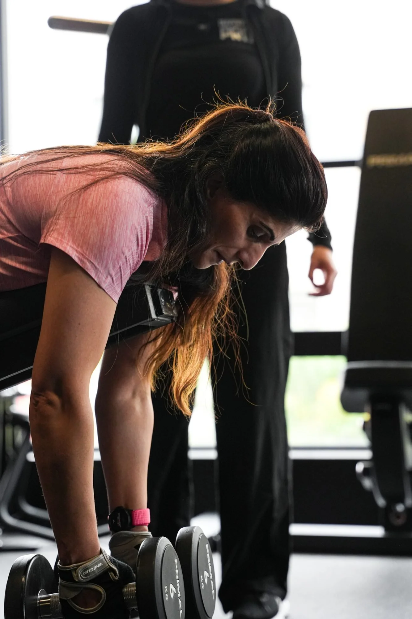 Member doing a dumbbell row with a coach beside her at Physique Pro Great Park