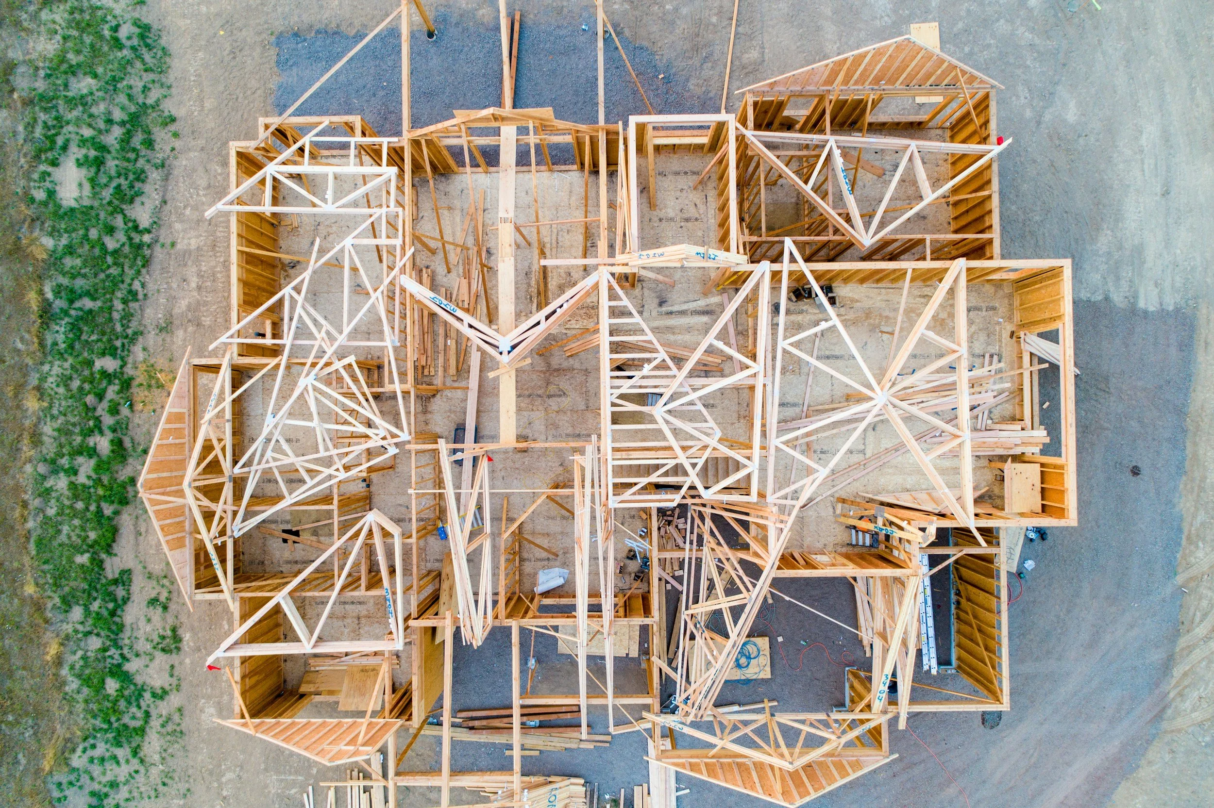 Aerial view of a house under construction with wooden framing and multiple rooms.