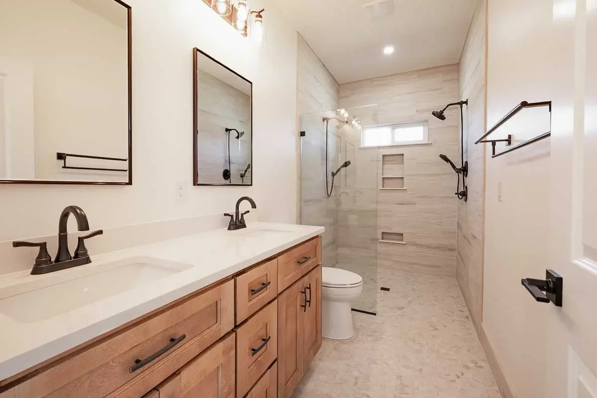 Spa style bathroom with wood cabinets and warm tile floors and walls, square mirrors, and oil rubbed bronze accents