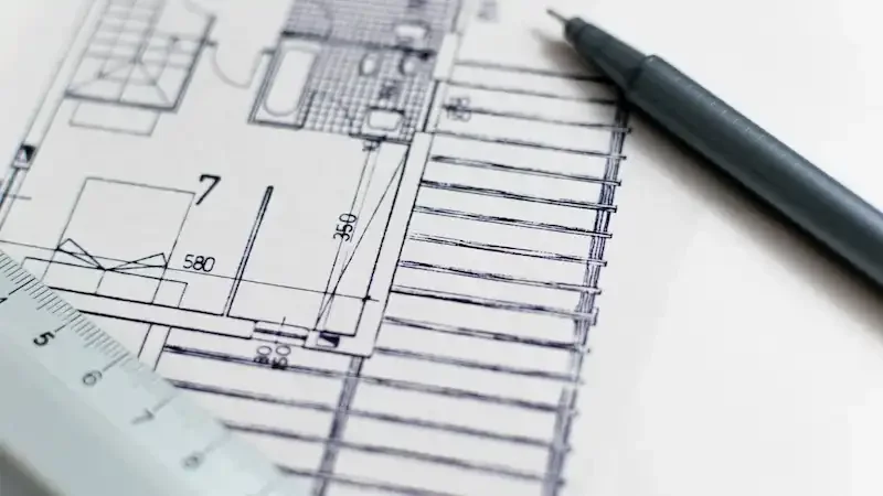 Architectural blueprint with a black pen and a ruler placed on top of it.
