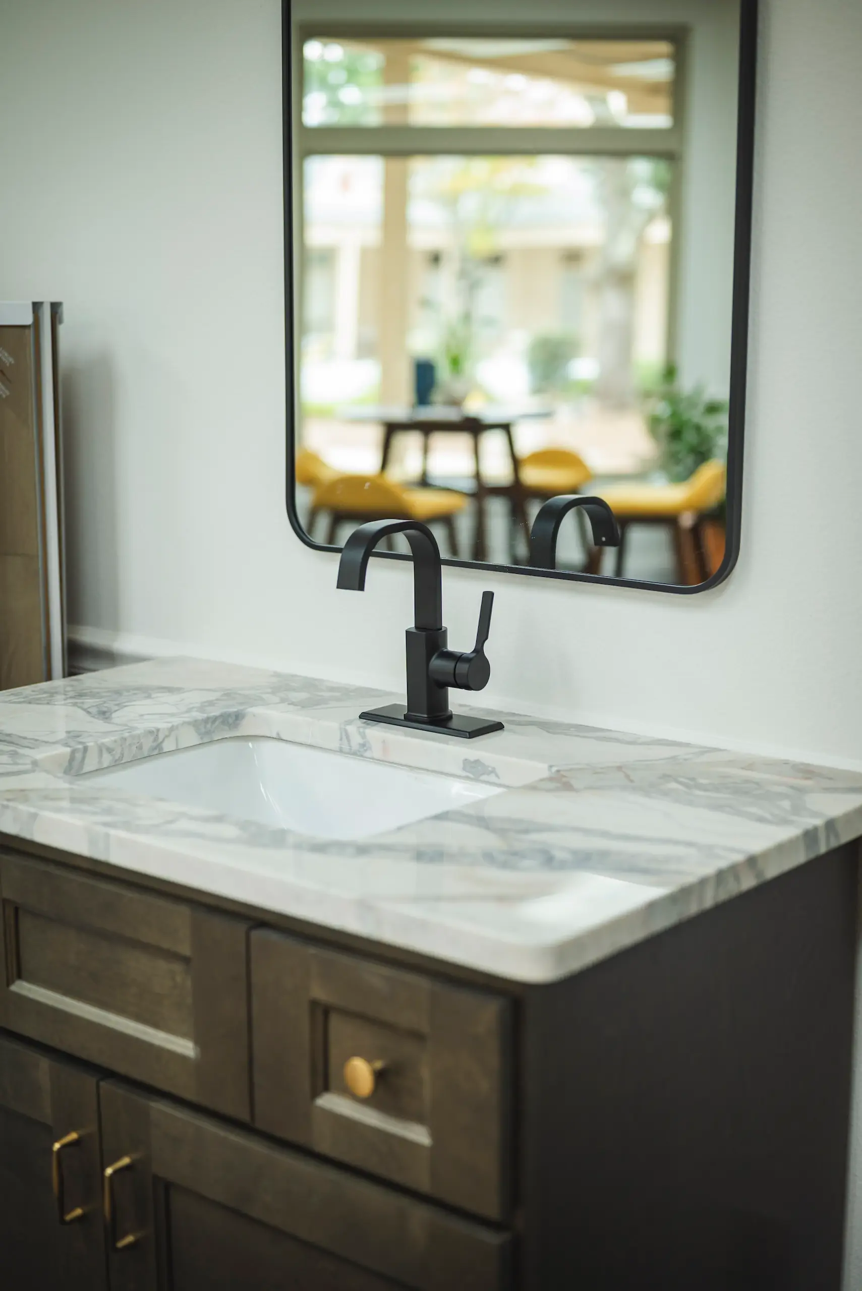 Marble countertop vanity with kodiak shaker base cabinet with gold hardware and black modern faucet with black beveled edge rectangular mirror on the wall