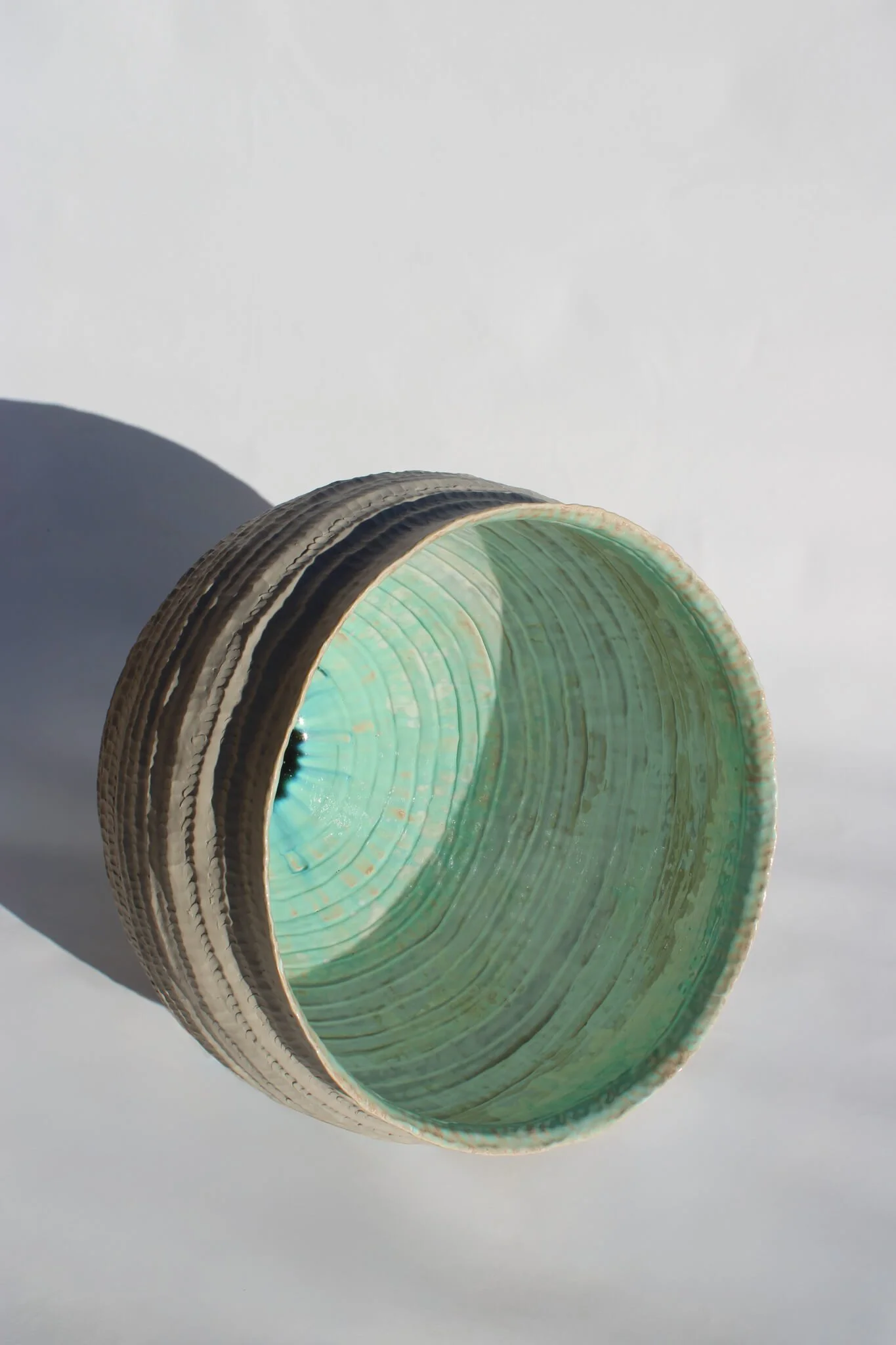 Side view of the reclined Primordial Vessel: a giant ceramic vessel sculpted out of ivory stoneware clay and containing crystalline glaze by multidisciplinary artist Noemie Marmara