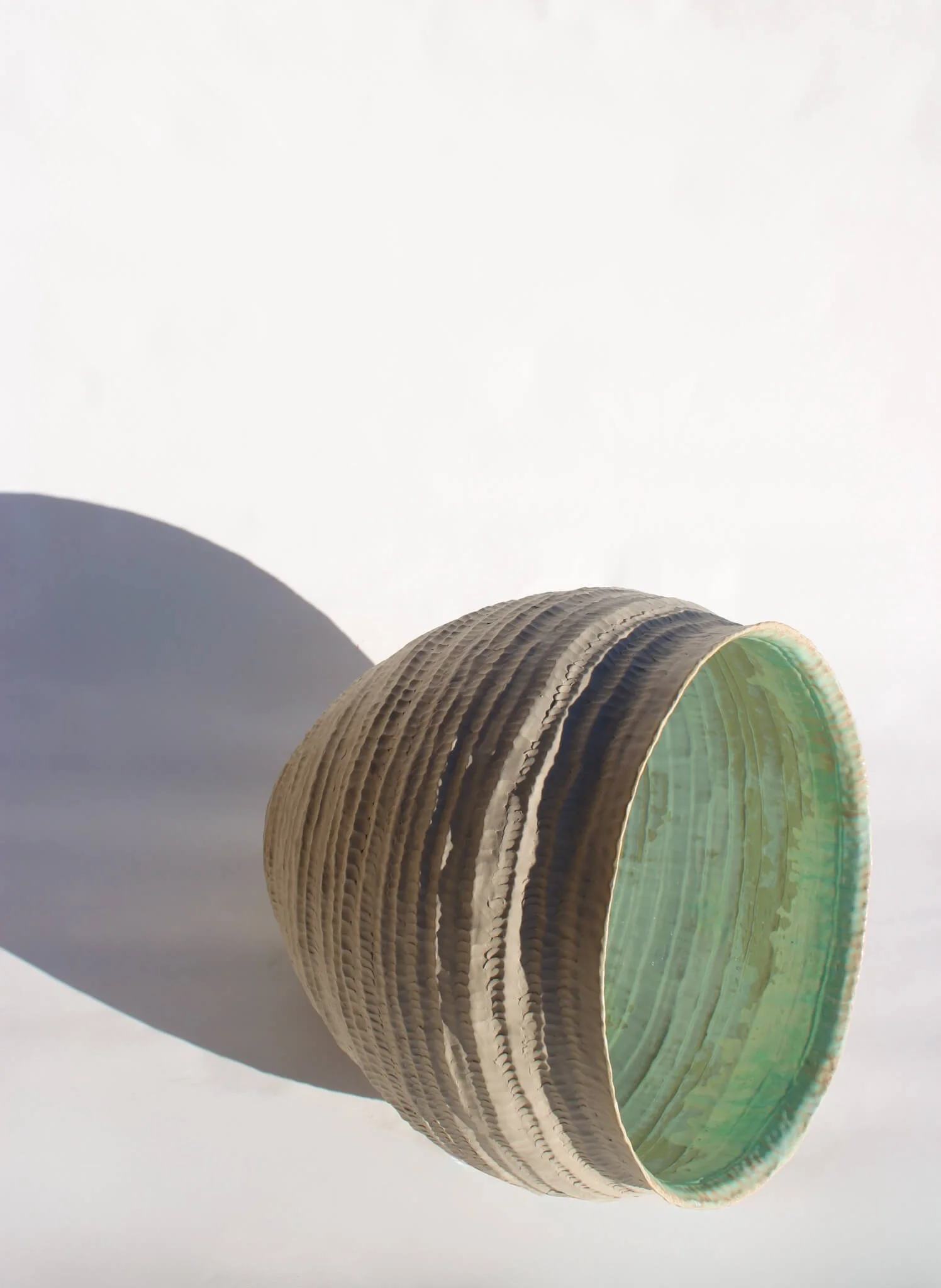 Side view of the reclined Primordial Vessel: a giant ceramic vessel sculpted out of ivory stoneware clay and containing crystalline glaze by multidisciplinary artist Noemie Marmara